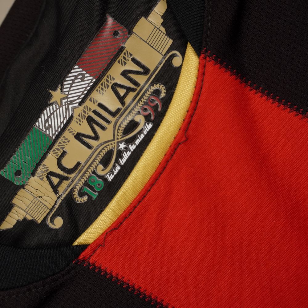 Dettaglio della grafica stampata all'interno del colletto della maglia del Milan con scudetto tricolore, logo del club, anni storici e il motto Tu sei tutta la mia vita.