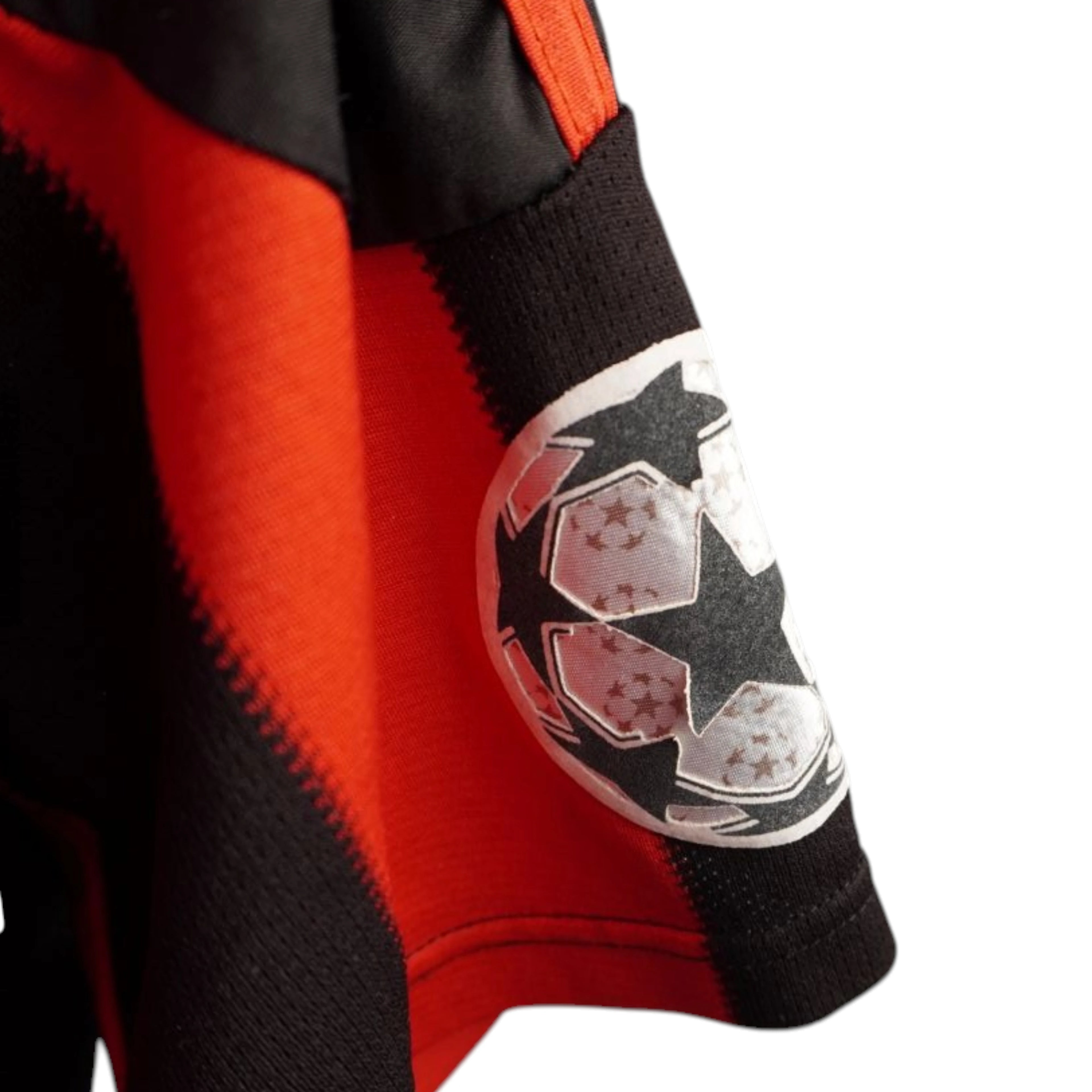 Primo piano del bordo manica della maglia del Milan che mostra la toppa Starball ufficiale della UEFA Champions League termoapplicata sul tessuto.