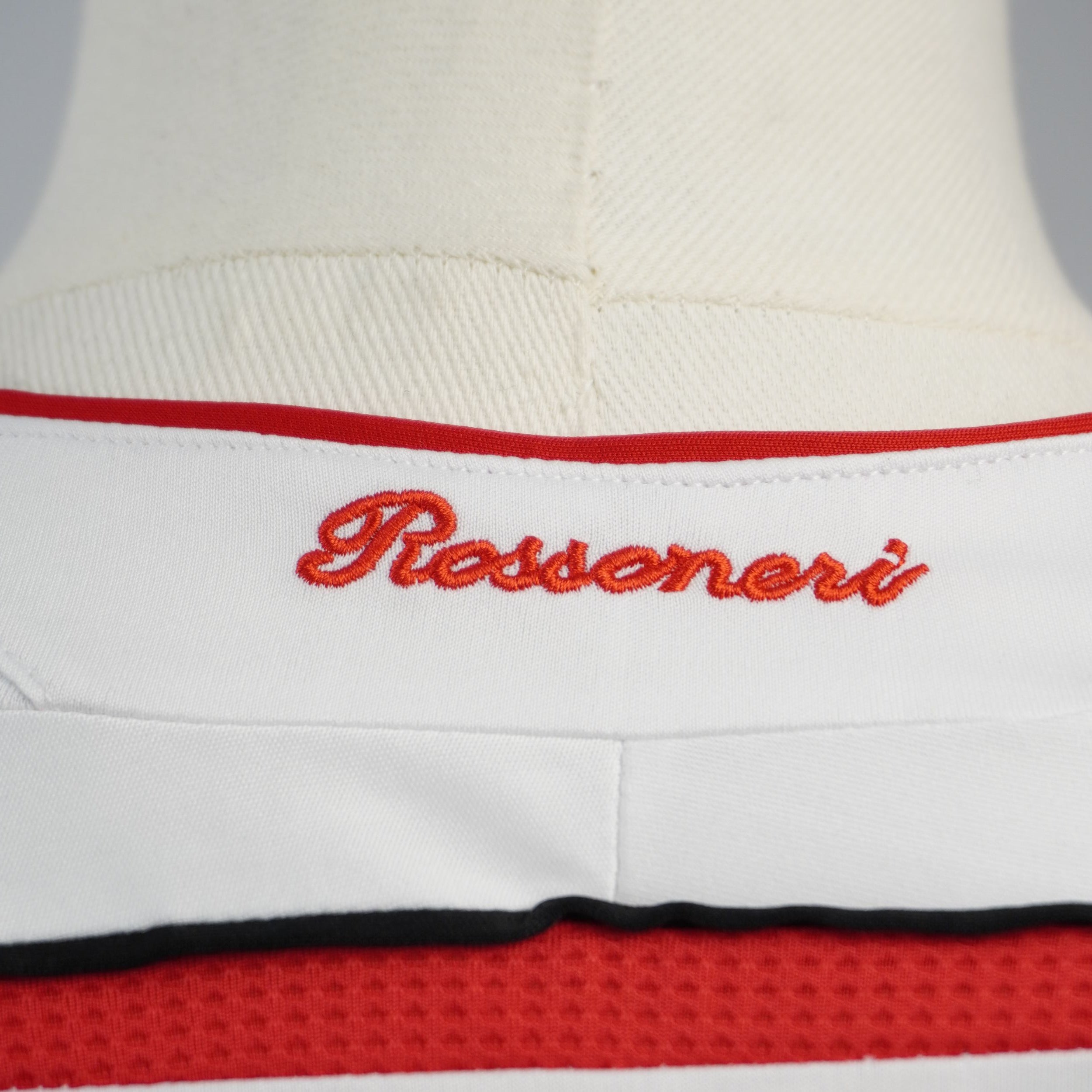 Dettaglio del ricamo rosso con la scritta Rossoneri sul retro del colletto della maglia bianca del Milan.