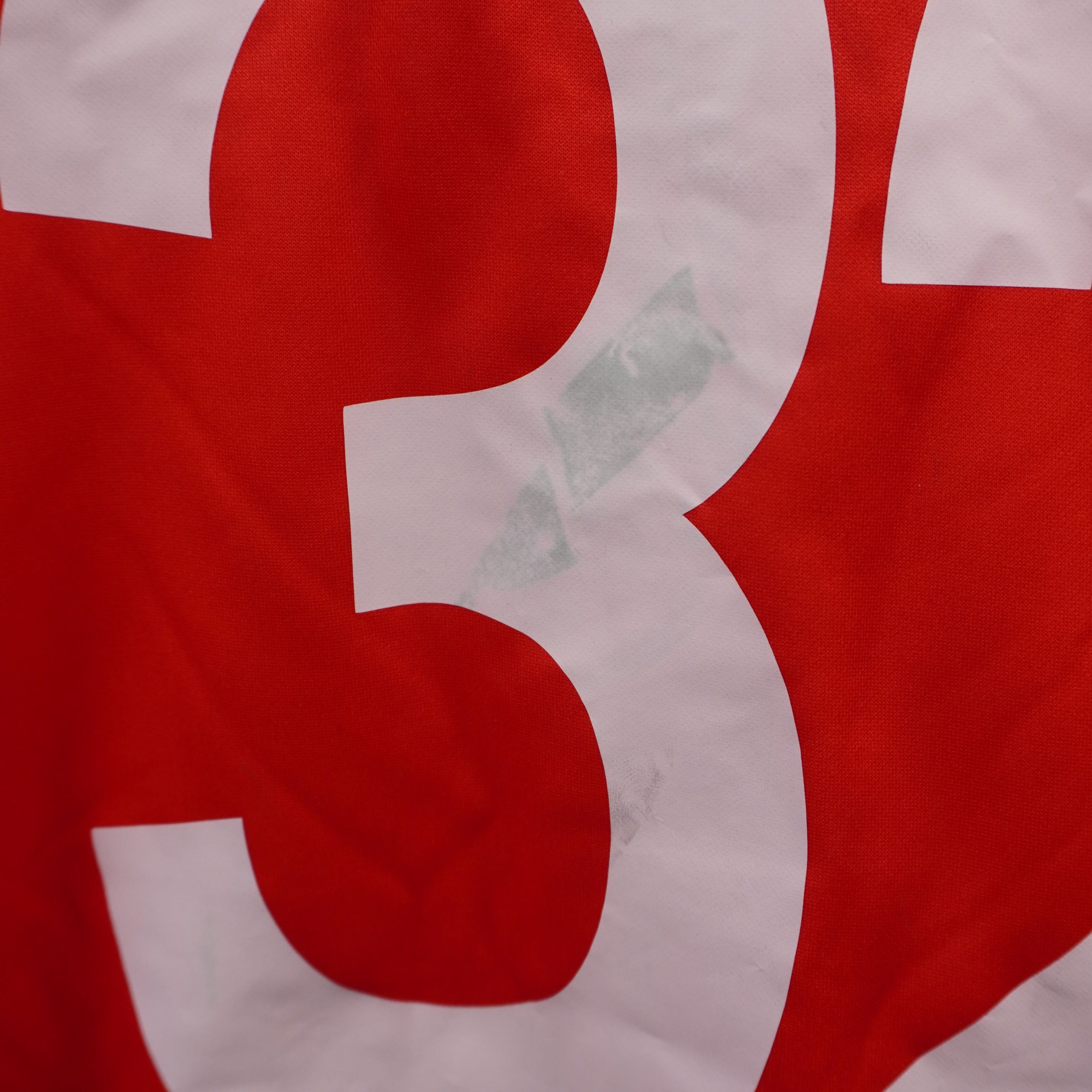 Evidenza del leggero trasferimento di colore grigiastro sul numero bianco posteriore della maglia.
