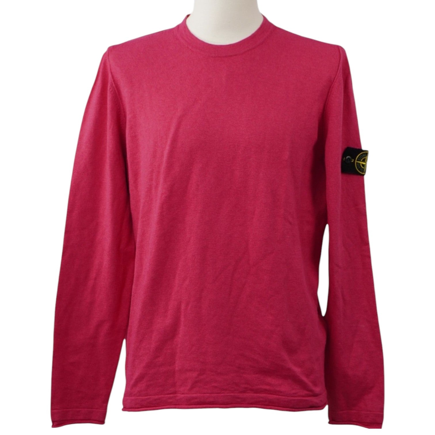Vista frontale su manichino di un maglione girocollo Stone Island a maniche lunghe color rosa ciclamino con l'iconico badge sulla manica sinistra.