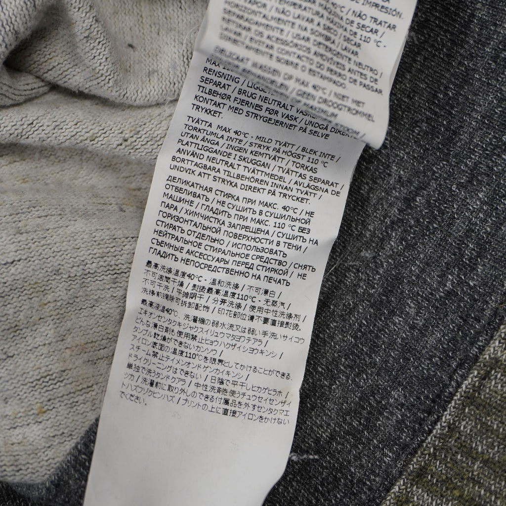 Dettaglio ravvicinato dell'etichetta di lavaggio multilingua internazionale del maglione Stone Island.