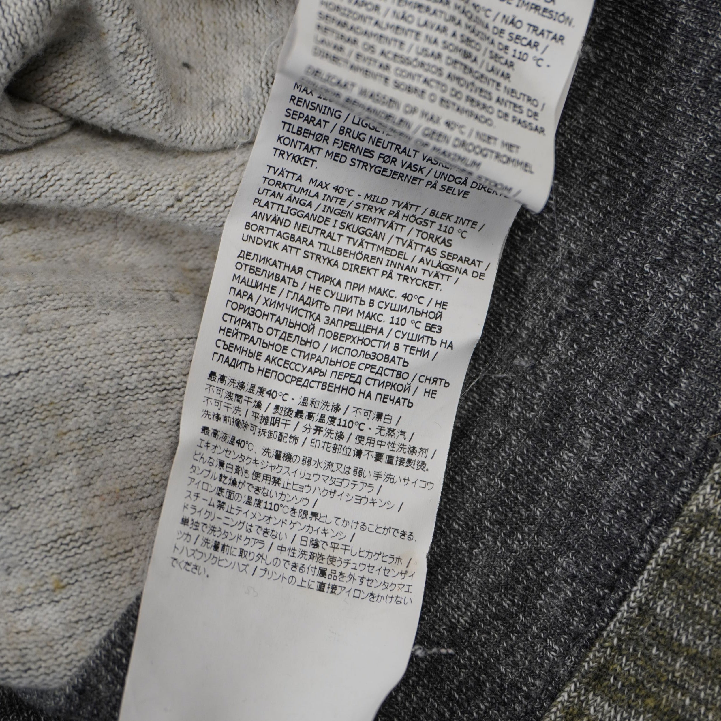 Dettaglio ravvicinato dell'etichetta di lavaggio multilingua internazionale del maglione Stone Island.