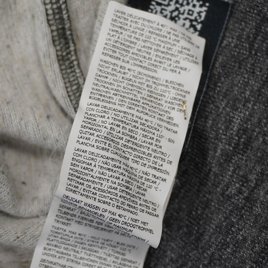 Dettaglio etichetta interna lavaggio multilingua maglione Stone Island a mezza zip.