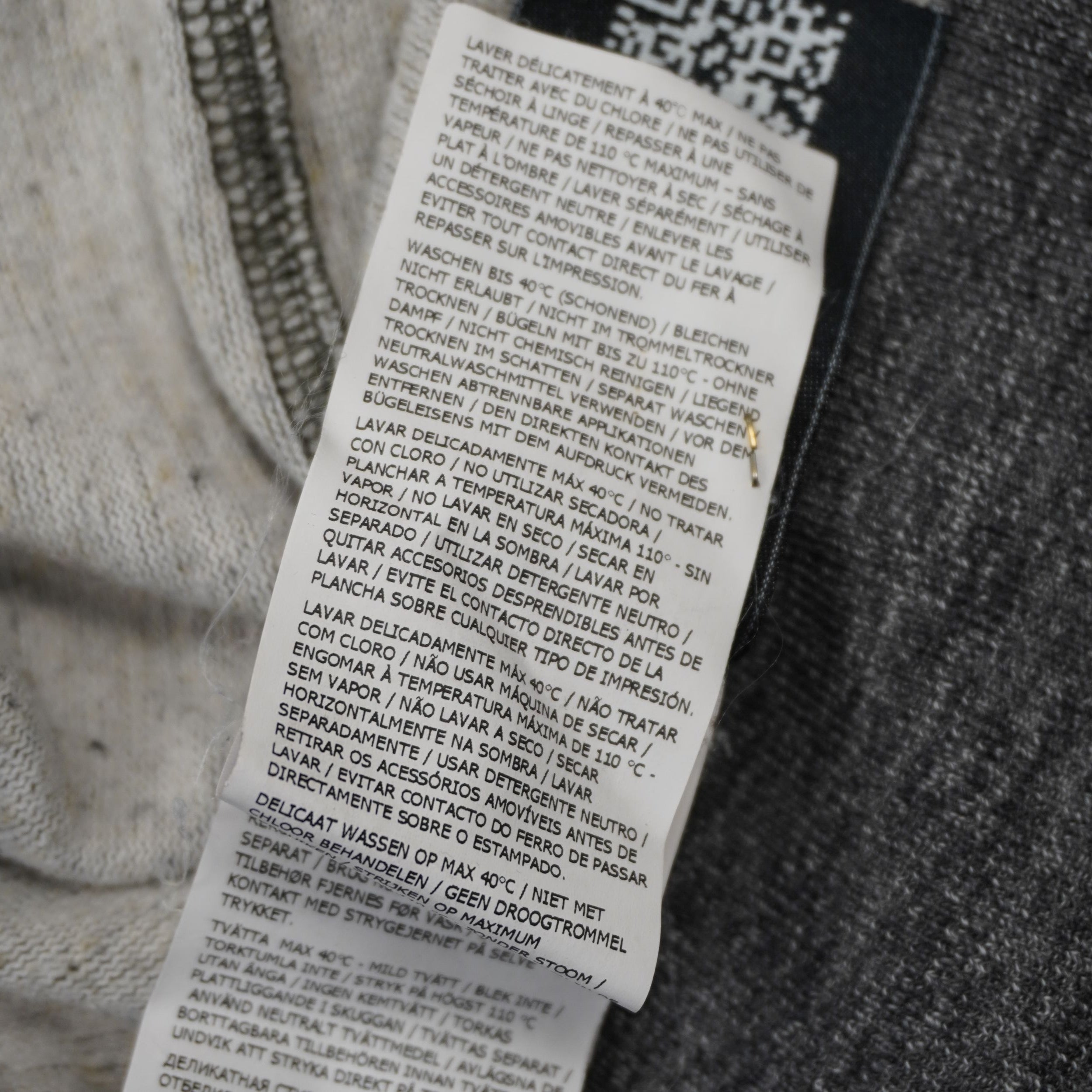 Dettaglio etichetta interna lavaggio multilingua maglione Stone Island a mezza zip.