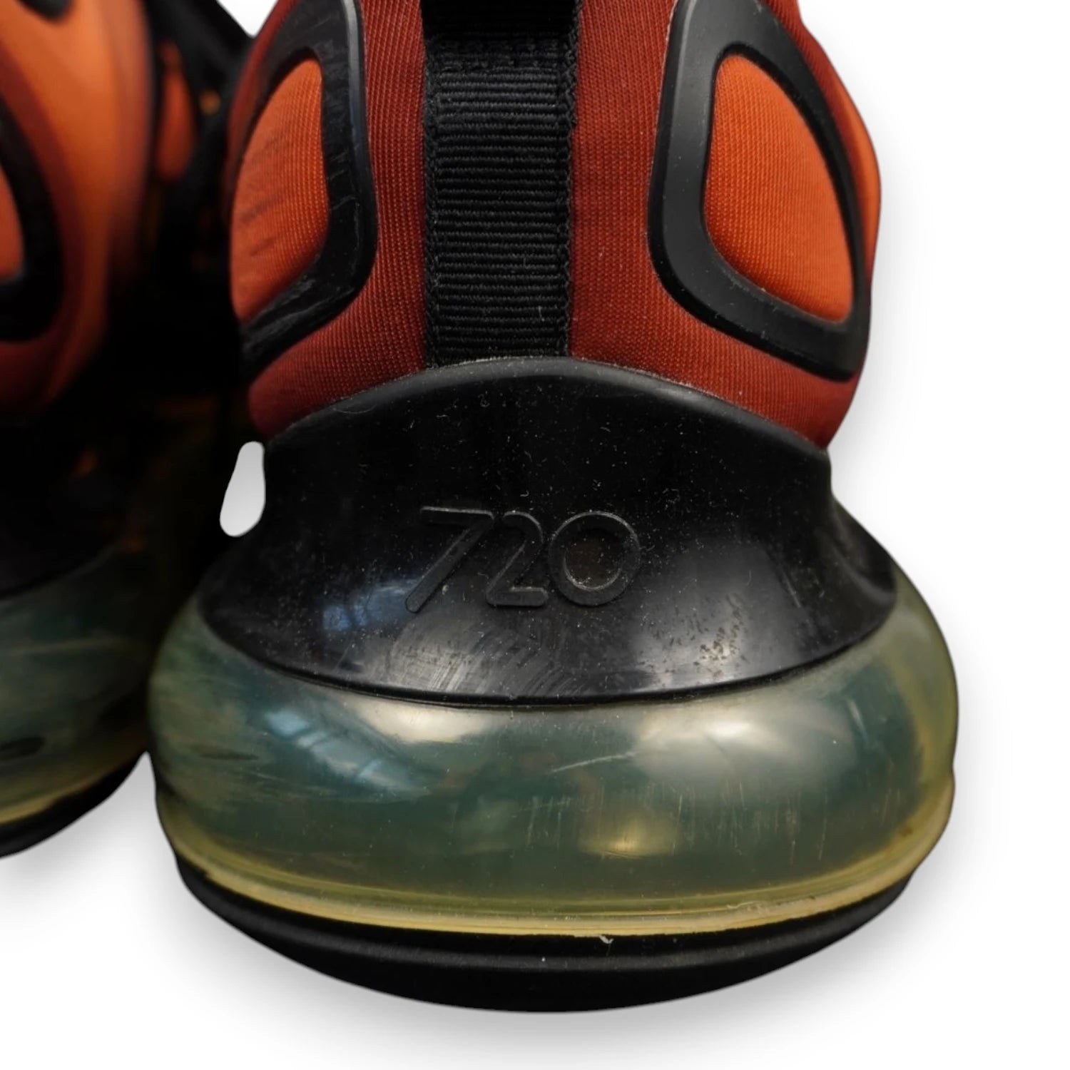 Macro del tallone delle Nike Air Max 720 Sunrise che mostra il logo inciso e lievi graffi superficiali sulla plastica nera.