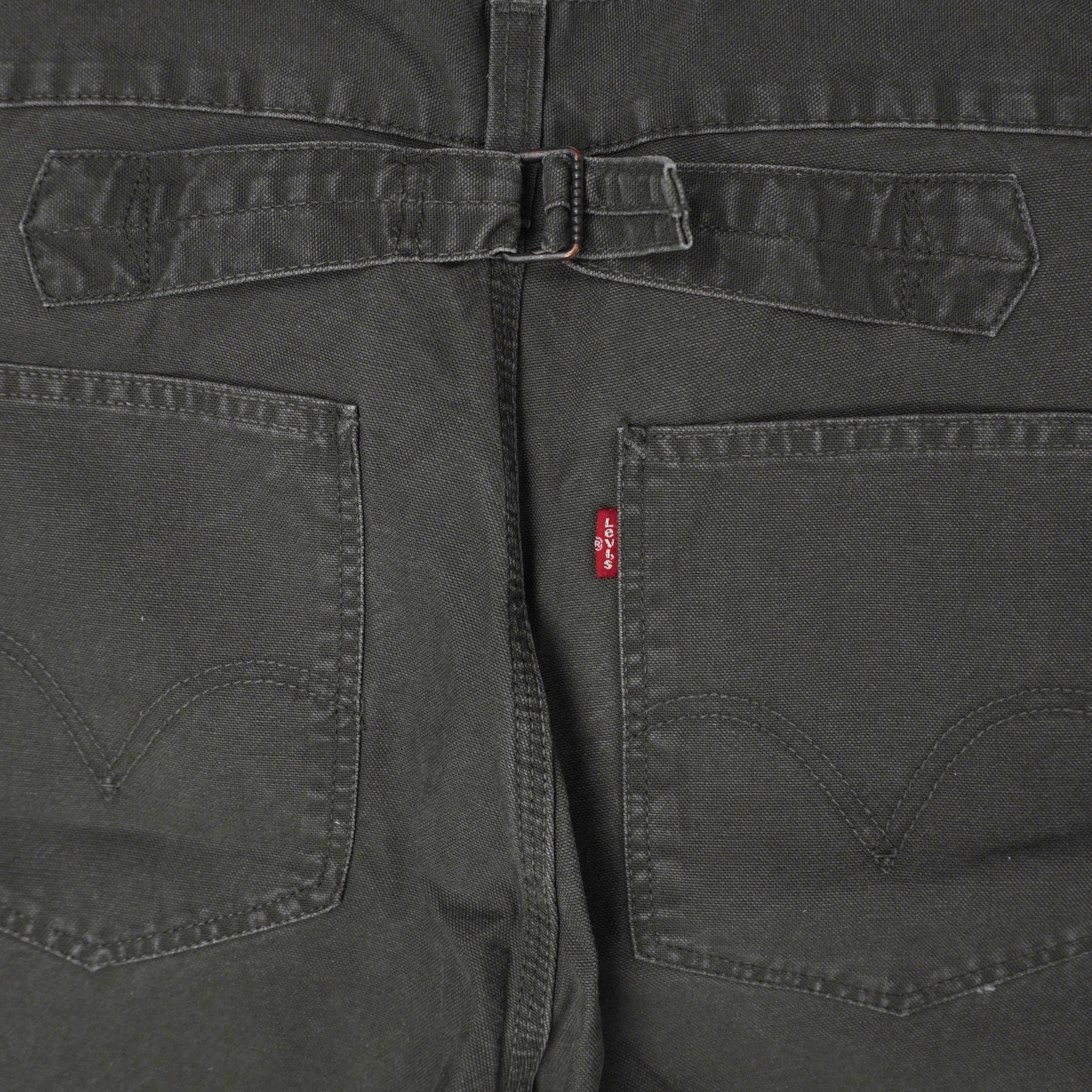 Primo piano macro della fibbia posteriore regolabile cinch back e dell'etichetta rossa Red Tab dei pantaloni Levi's.