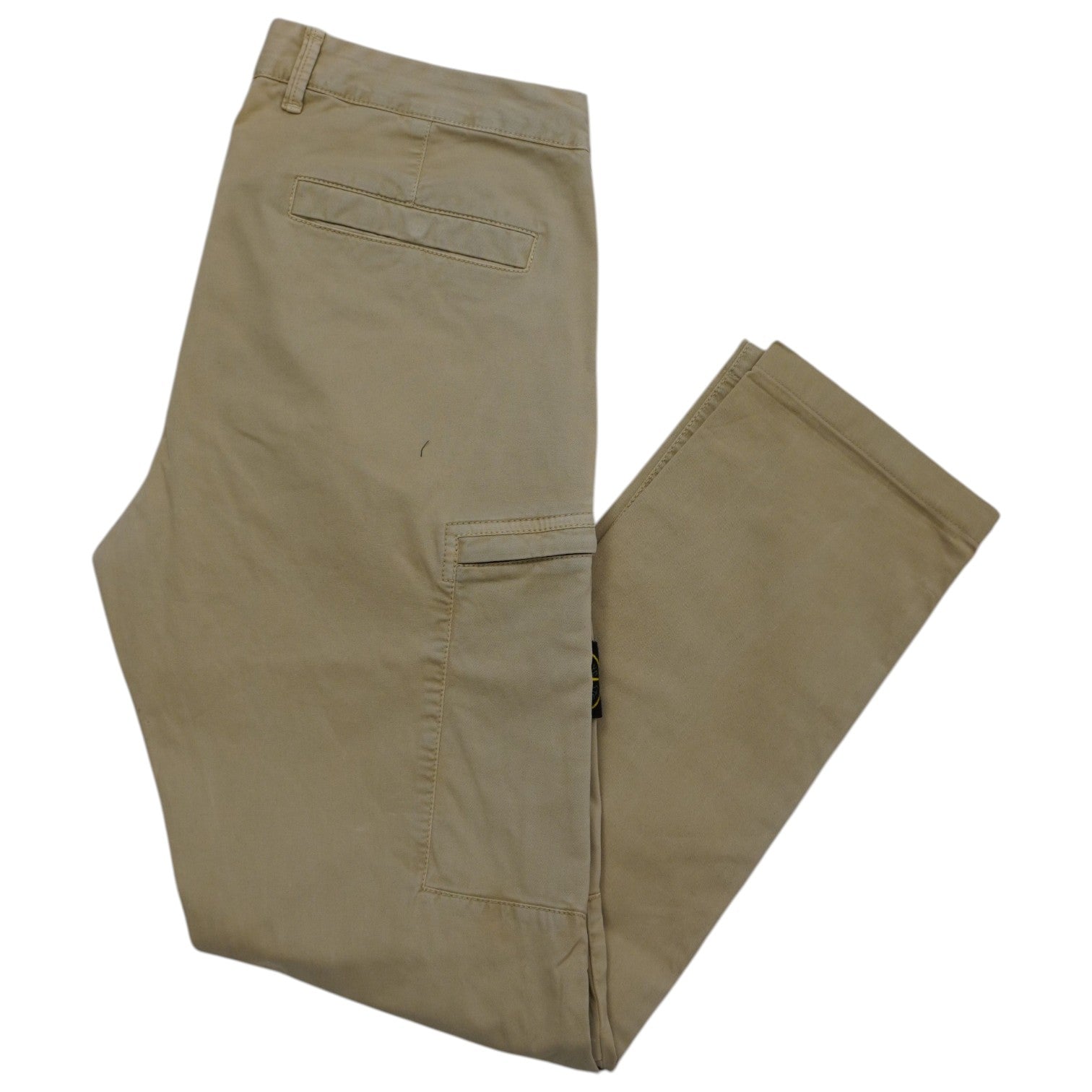 Vista d'insieme frontale di un pantalone cargo Stone Island TYPE SK in cotone elasticizzato beige sabbia piegato di profilo.
