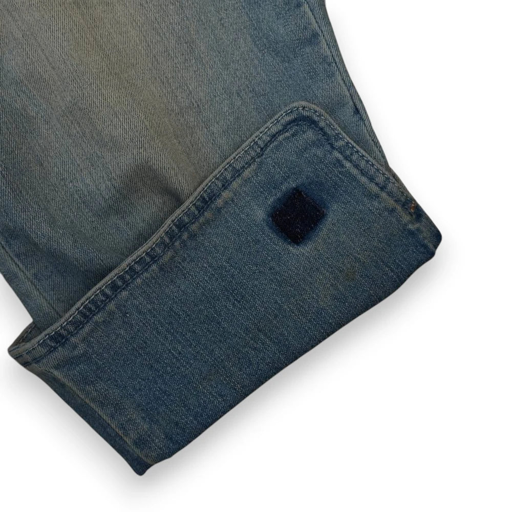 Zoom simmetrico sul fondo gamba opposto che mostra le doppie cuciture e la finitura pulita del risvolto in denim.