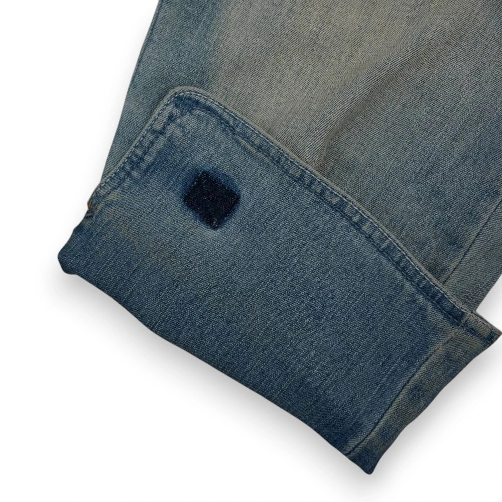 Dettaglio ravvicinato del maxi risvolto sul fondo gamba con linguetta quadrata in denim blu scuro a contrasto.