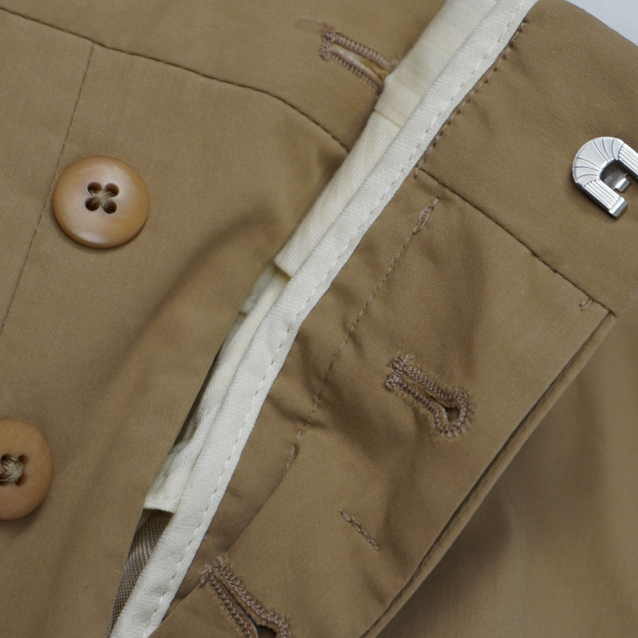 Dettaglio della chiusura interna a bottoni coperti e gancio metallico piatto sartoriale dei pantaloni Prada.