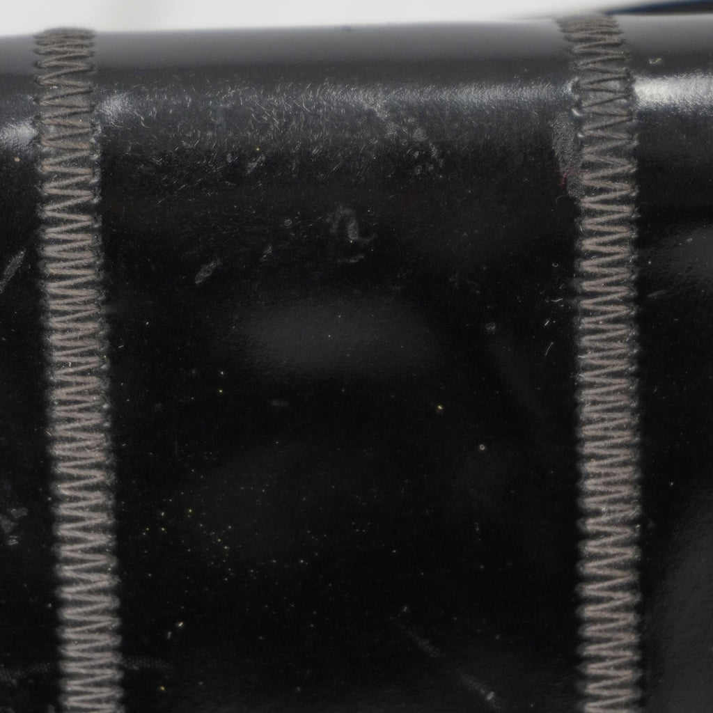 Macro della lavorazione artigianale a pannelli e delle cuciture tono su tono sulla pelle verniciata della borsa Fendi.