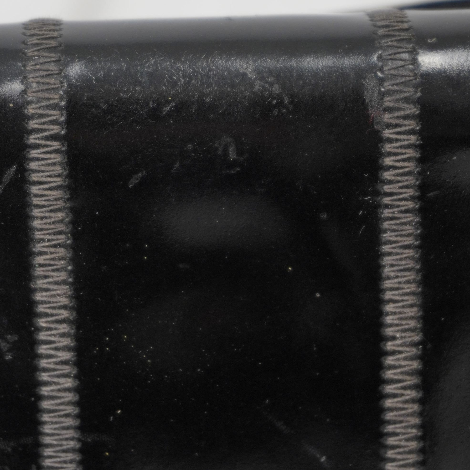 Macro della lavorazione artigianale a pannelli e delle cuciture tono su tono sulla pelle verniciata della borsa Fendi.