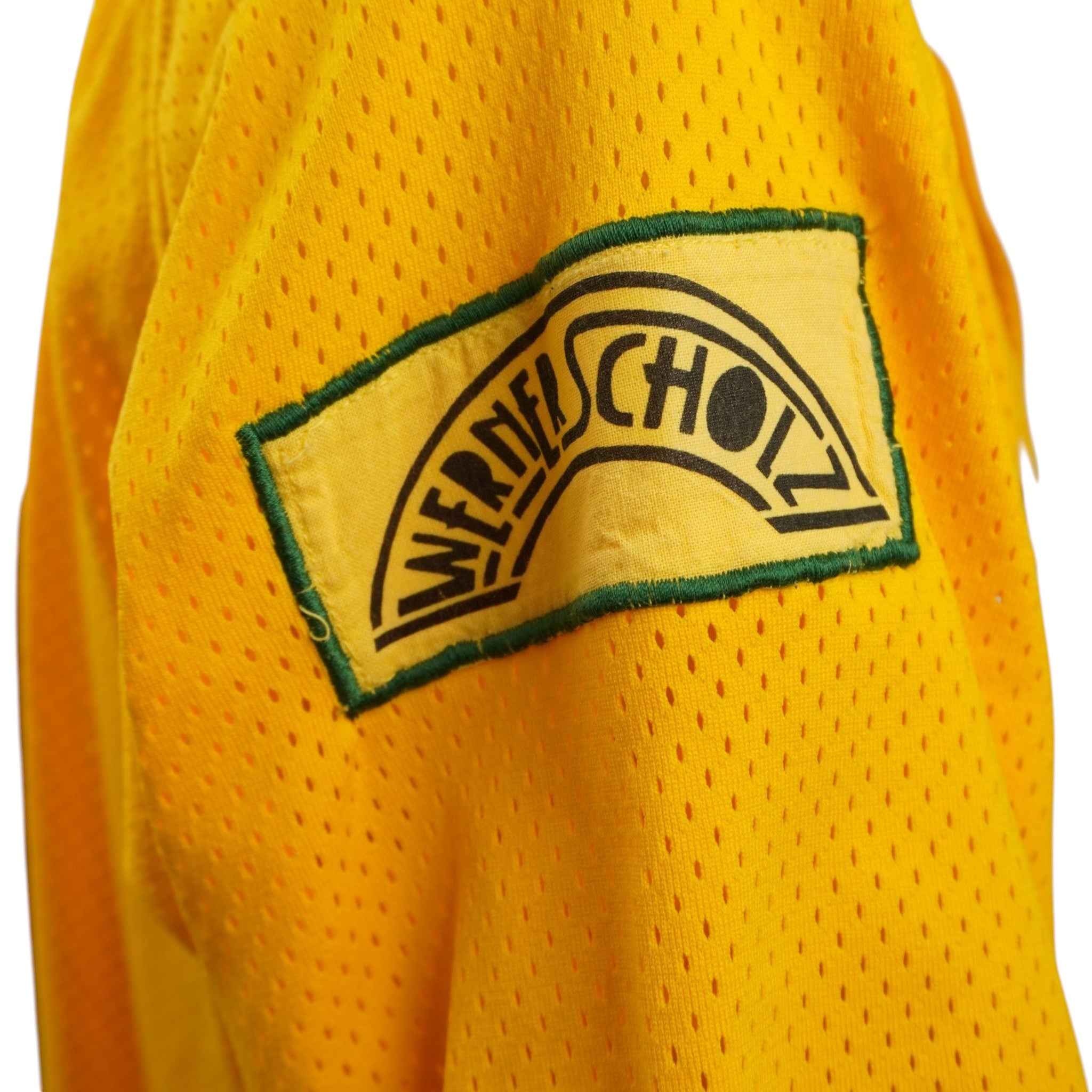  Particolare della patch verde ricamata applicata sulla manica della maglia da baseball, dettaglio stilistico aggiuntivo.