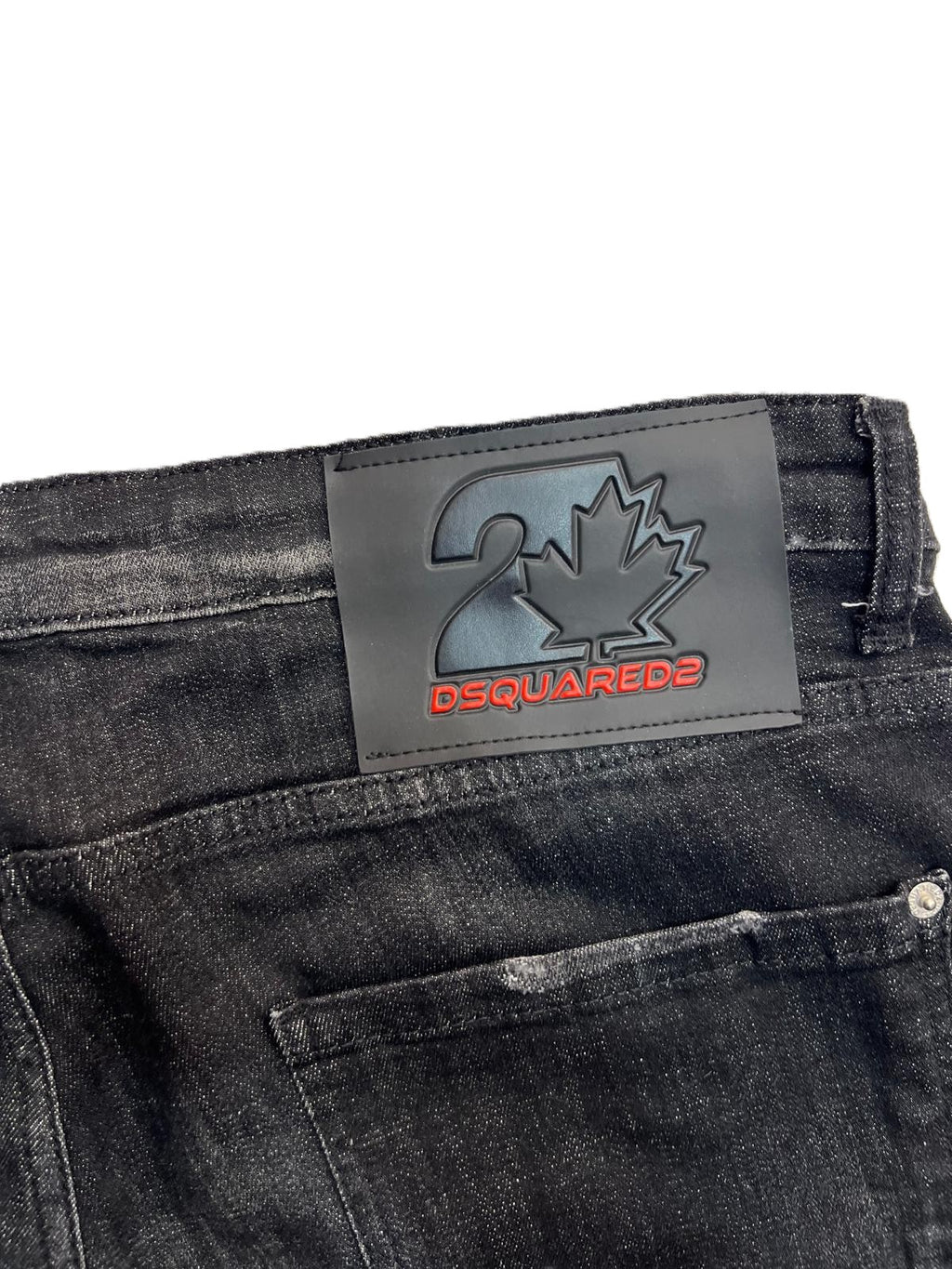 Dettaglio della salpa posteriore in pelle scura con logo impresso sul retro dei jeans Dsquared2.