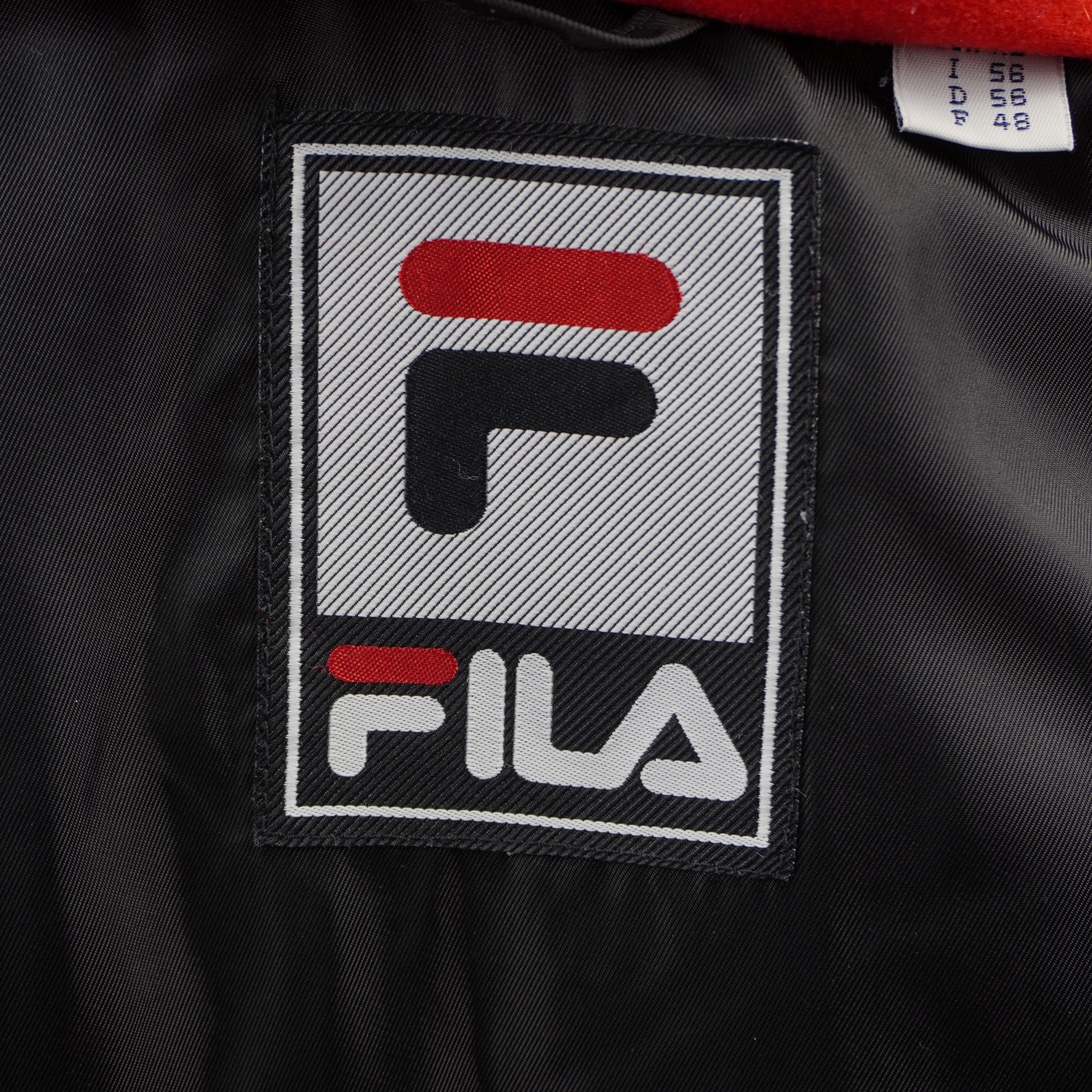Particolare della classica patch quadrata Fila con logo blu e rosso applicata sulla parte frontale del piumino.