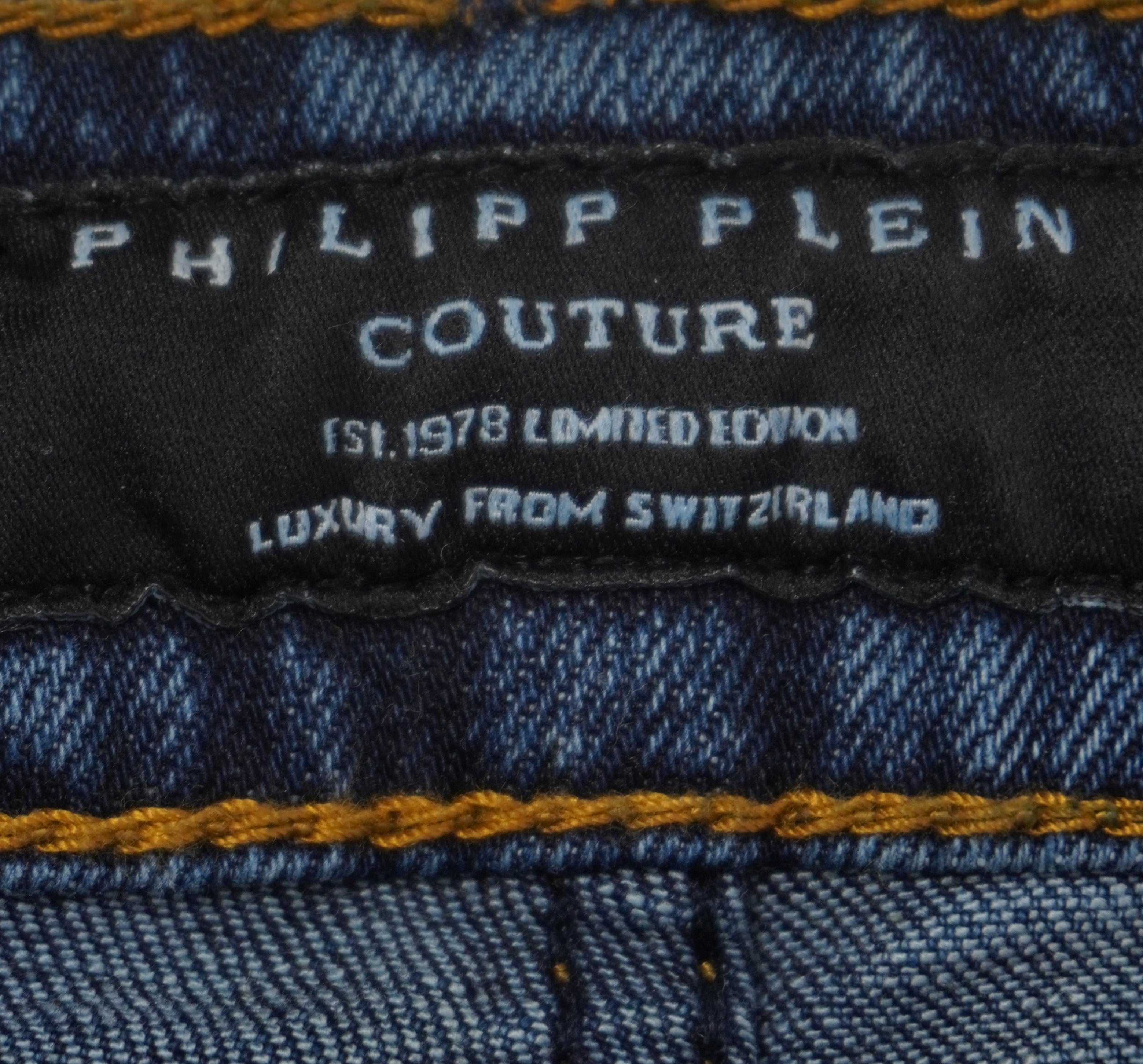 Macro del ricamo bianco su tessuto nero dell'etichetta interna Philipp Plein Couture sulla cintura dei jeans