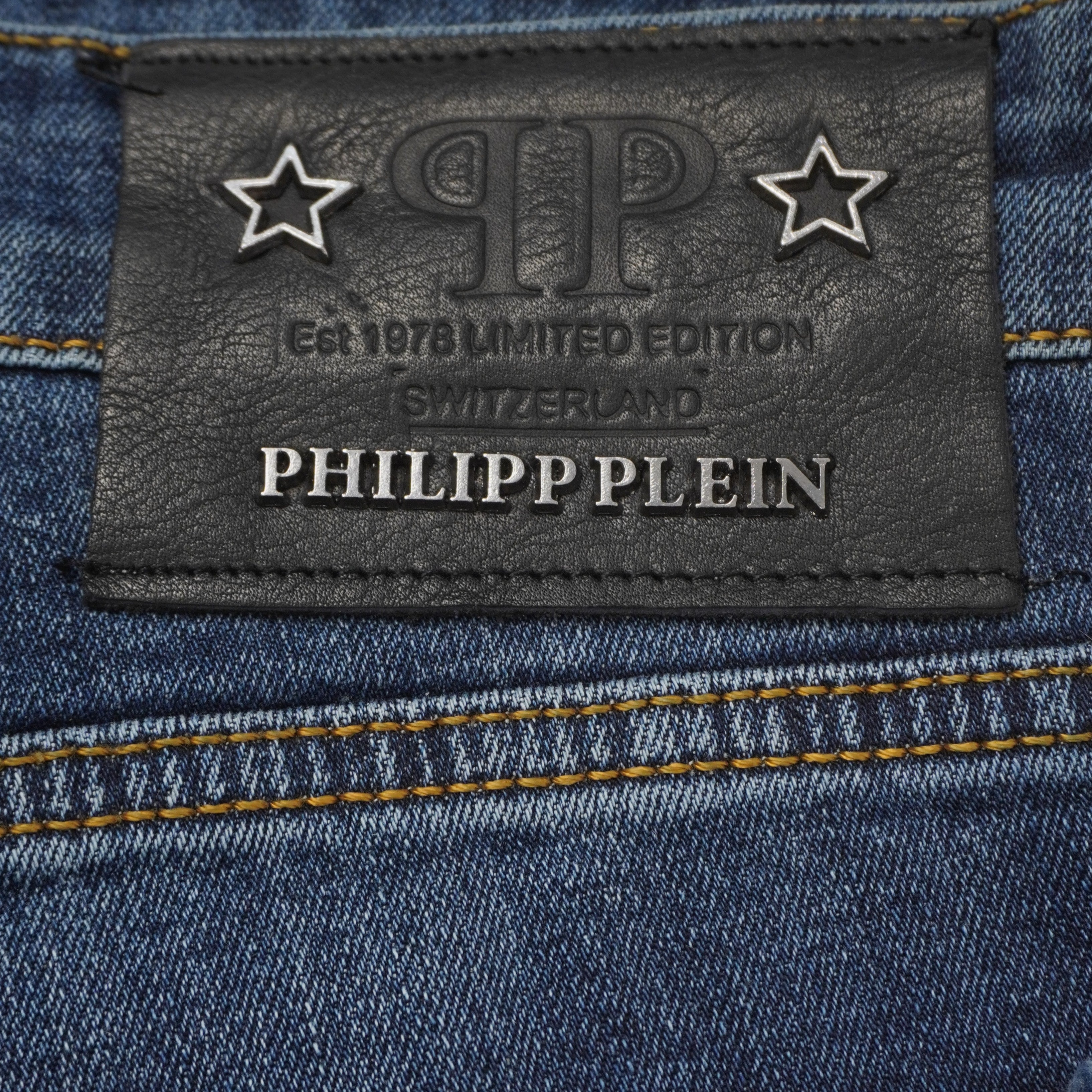 Primo piano macro della patch posteriore in pelle nera dei jeans Philipp Plein con stelle metalliche e scritte