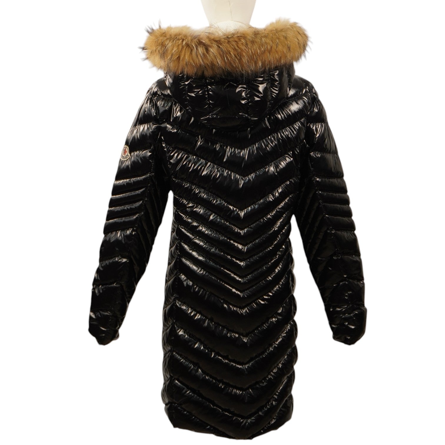 Vista posteriore del piumino lungo Moncler nero sul manichino, che evidenzia il design trapuntato a spina di pesce che sfila la silhouette.