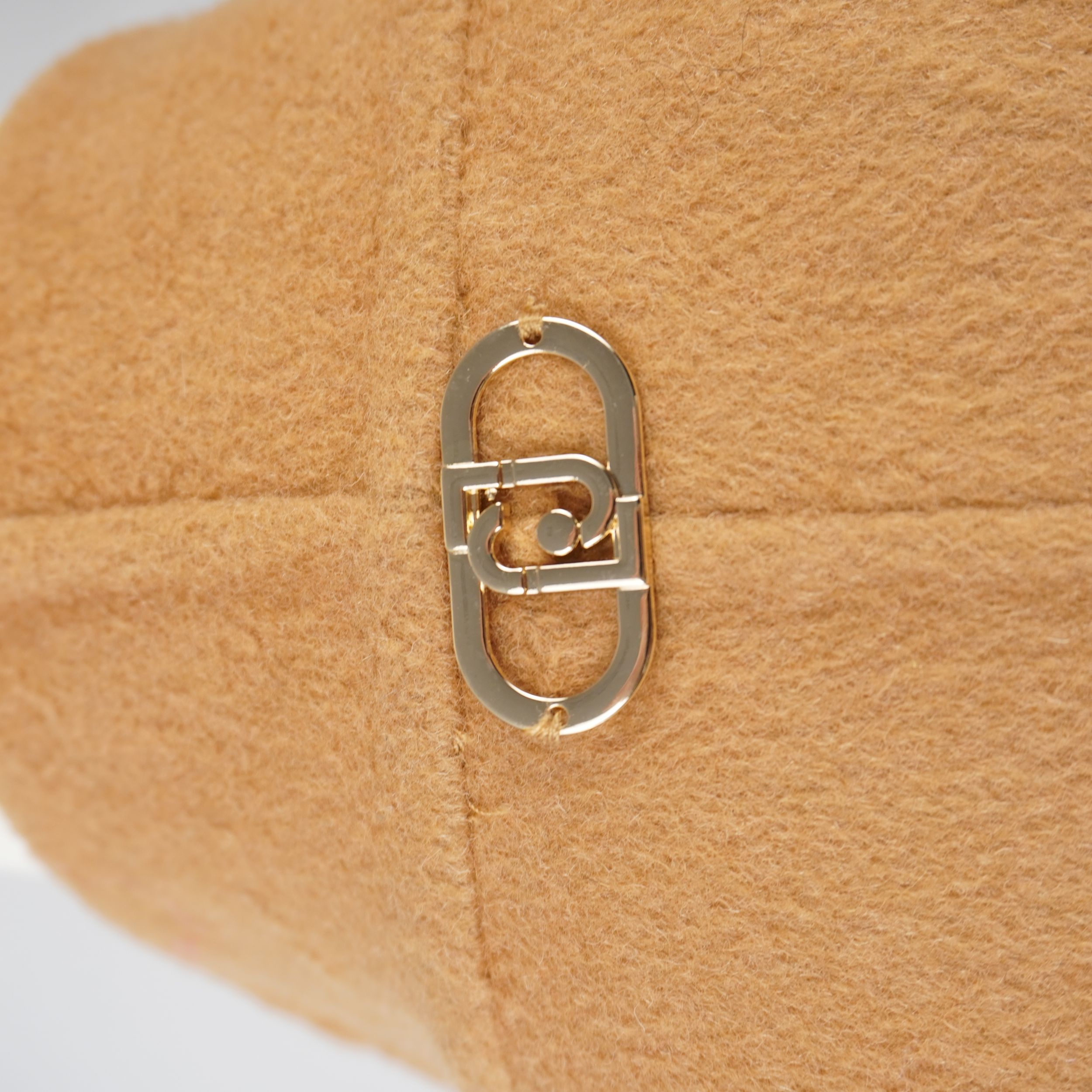 Particolare della placca ovale dorata con logo LJ incastonata sul retro del colletto del cappotto Liu Jo.