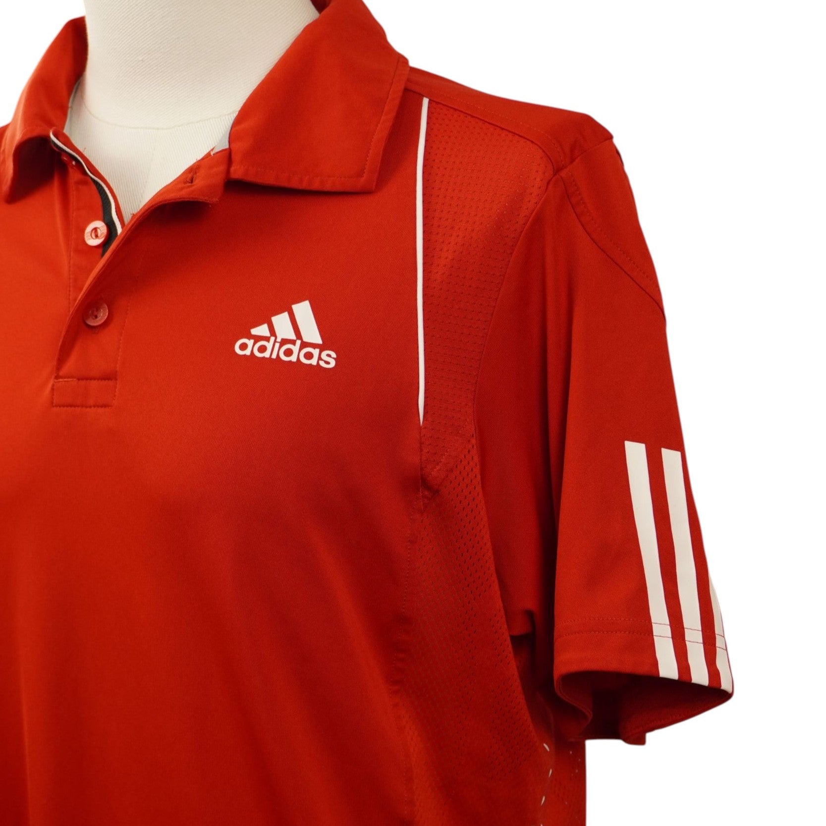 Primo piano laterale della polo Adidas che evidenzia le iconiche tre strisce bianche verticali sulla manica e il profilo sulla spalla.