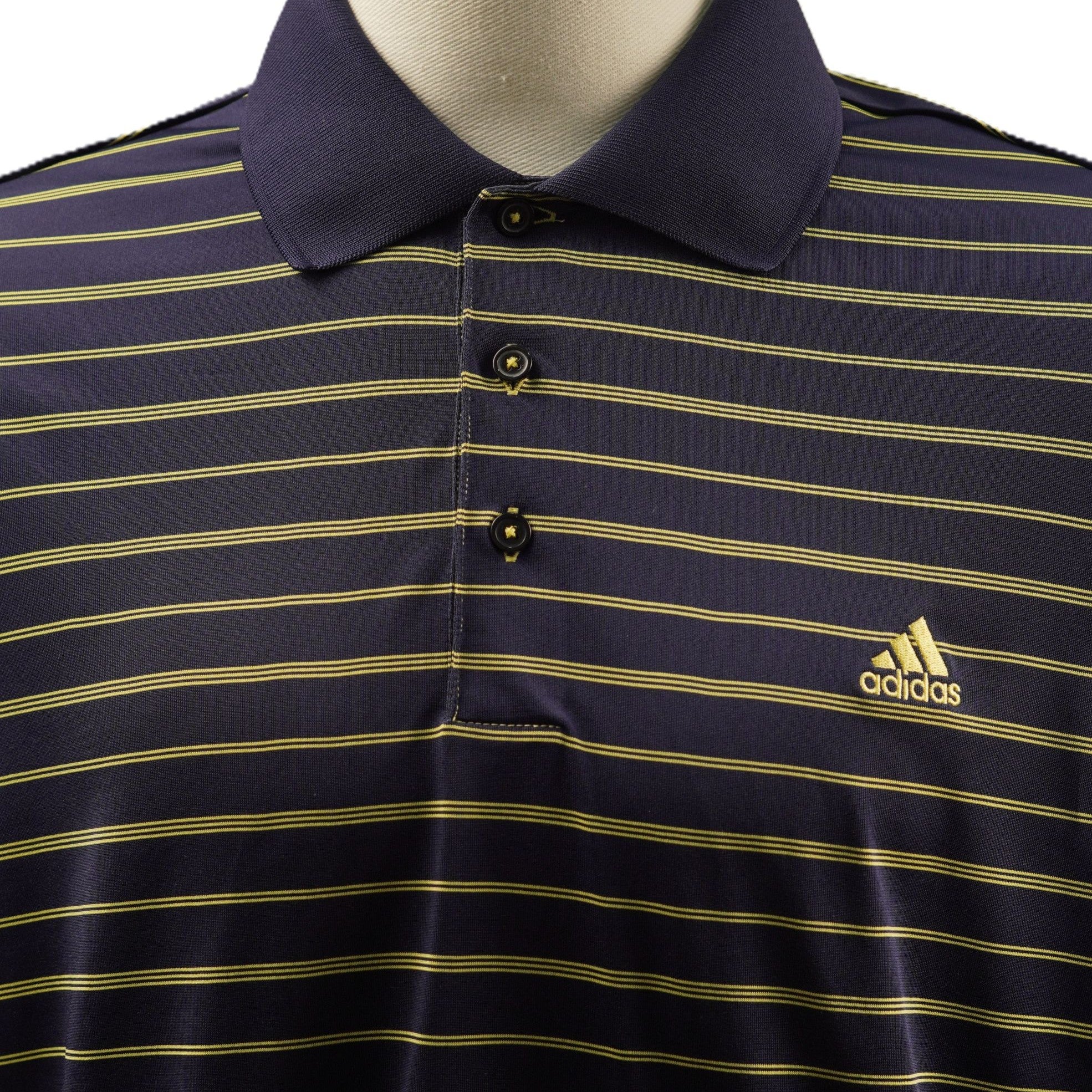 Primo piano della parte superiore della polo adidas blu navy con focus sul colletto classico in maglia e sul logo giallo ricamato.
