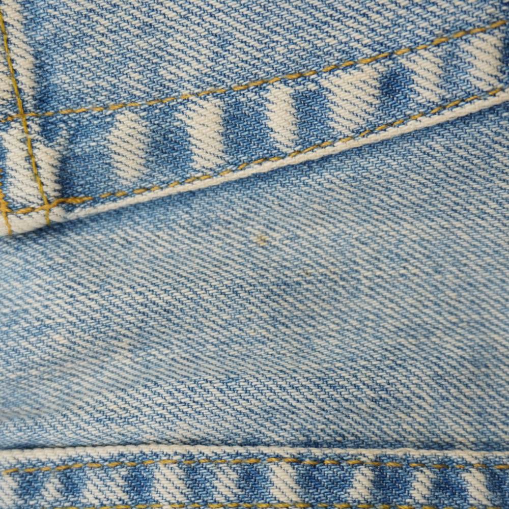 Inquadratura ravvicinata tra le cuciture della minigonna in jeans che evidenzia una micro macchiolina ombreggiata.