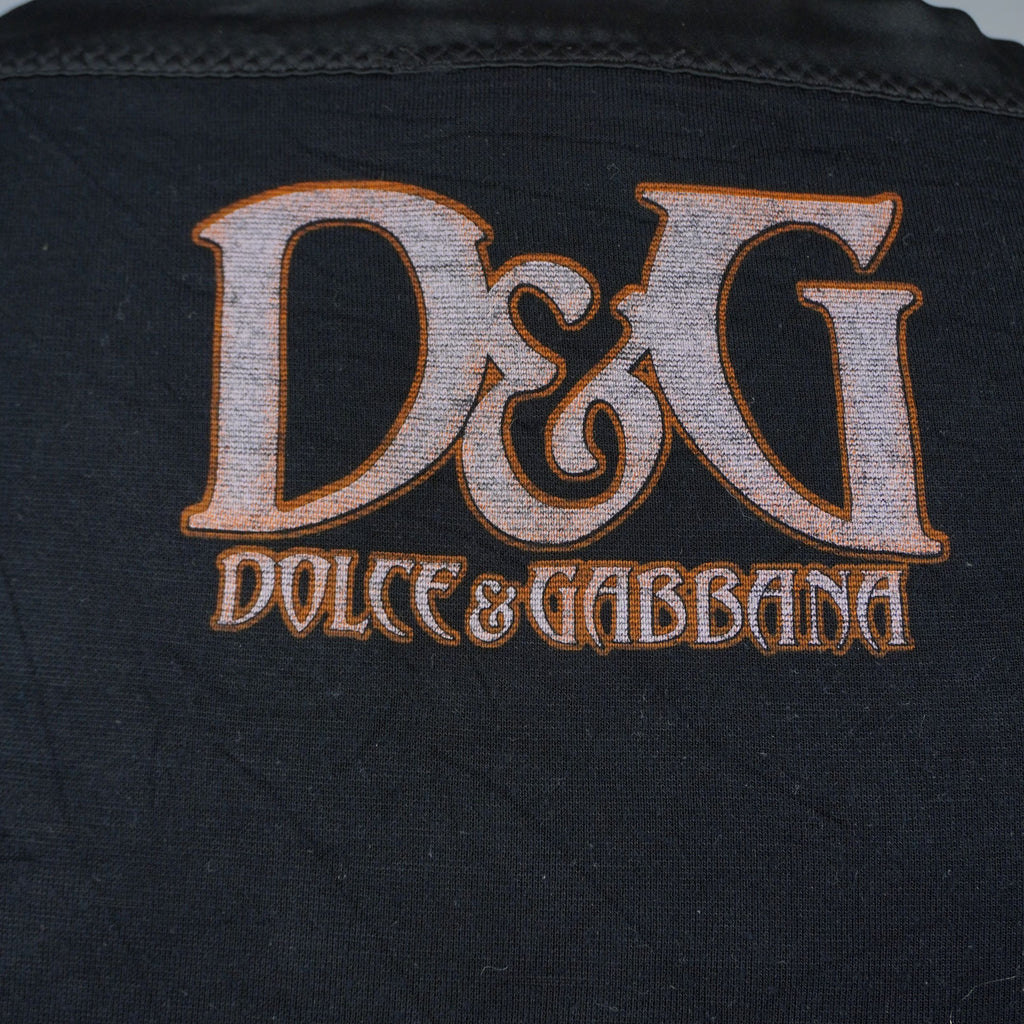 Macro sul maxi logo D&G Dolce & Gabbana stampato sul retro in tessuto nero con caratteri in stile gotico color bronzo.
