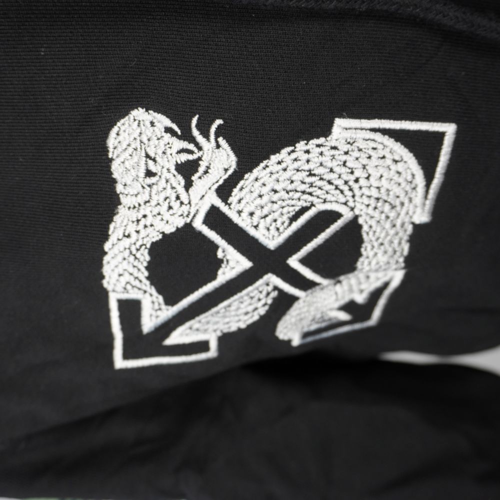 Particolare del logo Arrows avvolto dal serpente ricamato sul lato destro del petto