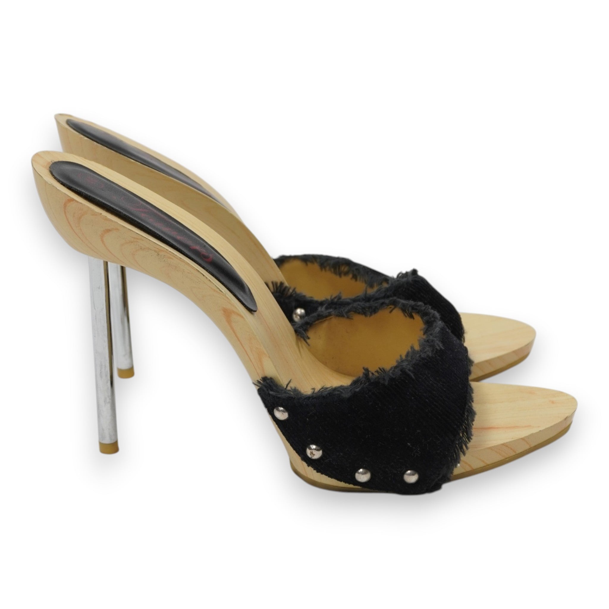 Inquadratura laterale di profilo delle scarpe Towers con tacco stiletto metallico lucido, borchie argentate sulla tomaia e suola sagomata in legno.