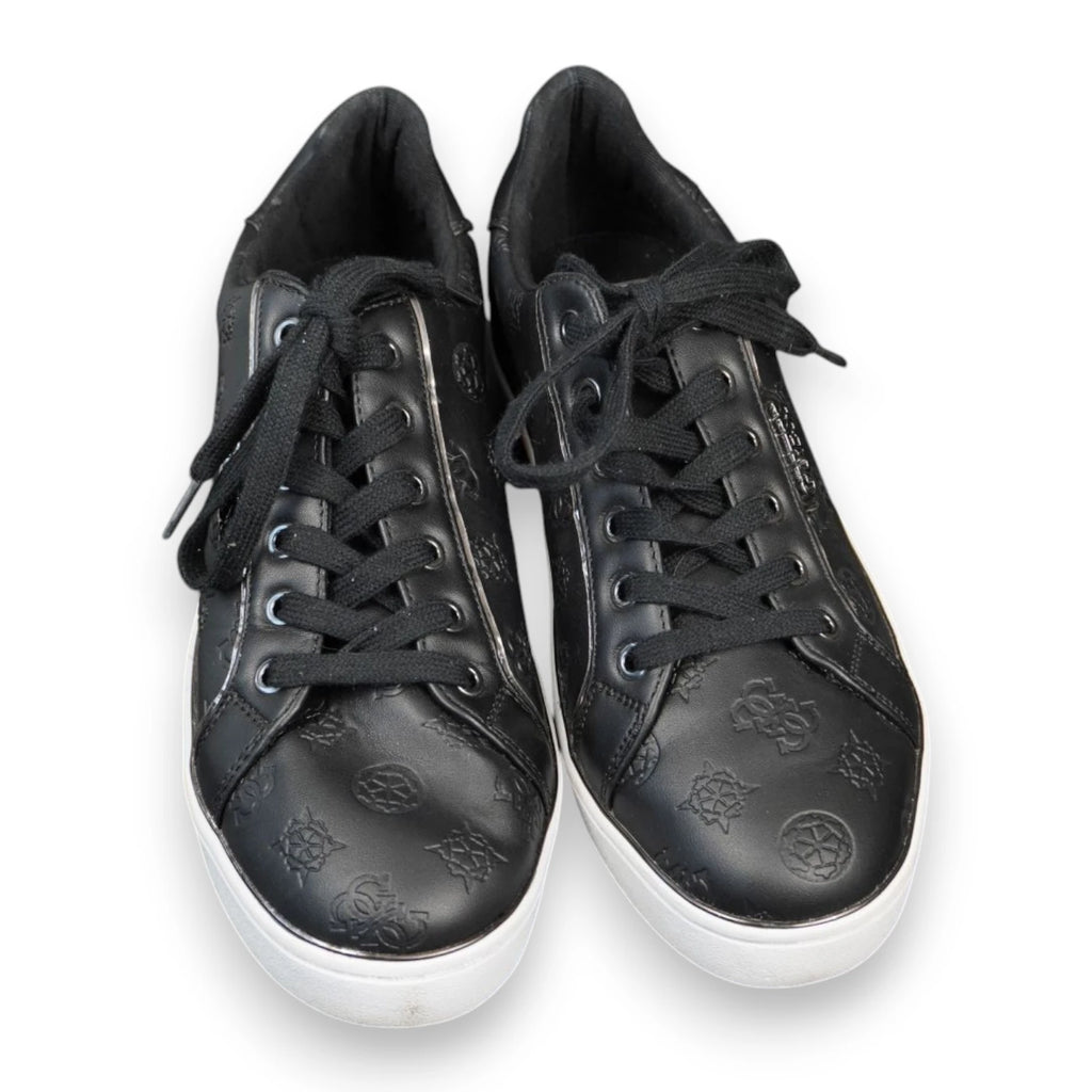 Inquadratura dall'alto a tre quarti di un paio di sneakers nere Guess con stringhe nere