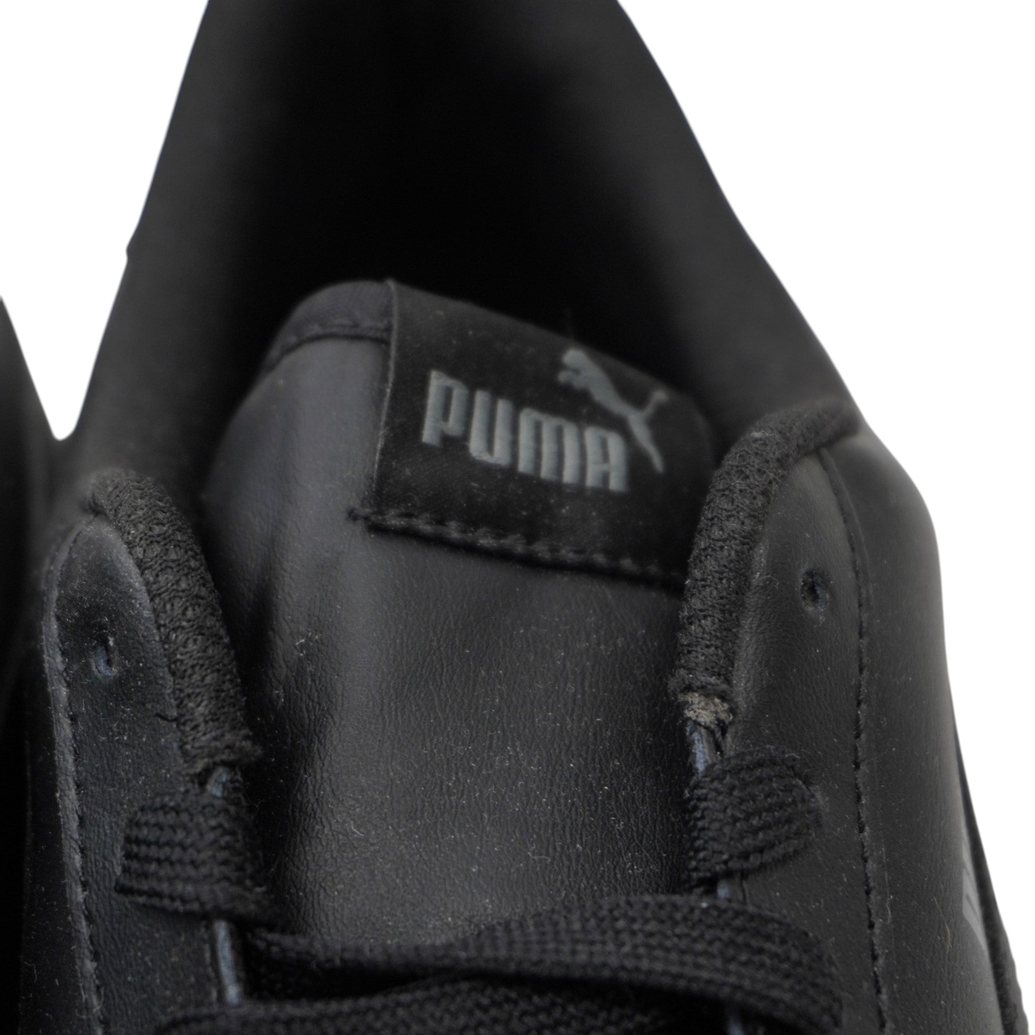 Primo piano dell'etichetta nera con logo grigio cucita sulla linguetta delle PUMA Smash.
