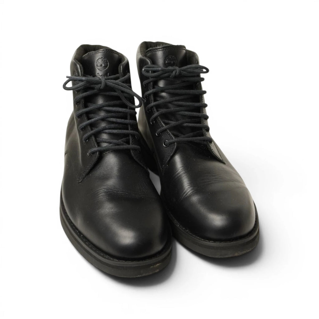 Vista di tre quarti degli scarponcini chukka Timberland neri da uomo in vera pelle su sfondo bianco.