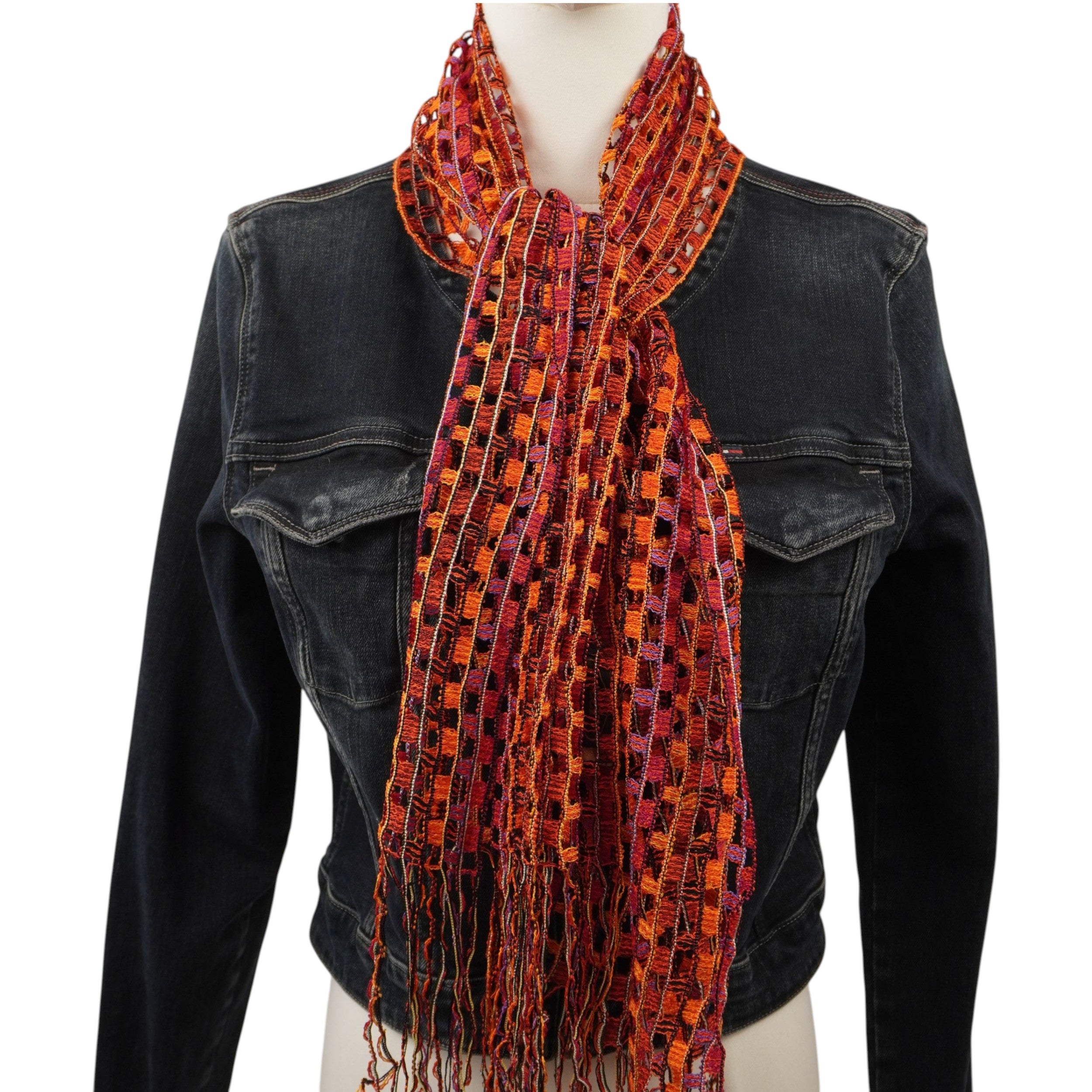 Sciarpa vintage Missoni a rete multicolor arancio e rossa con frange, indossata su un manichino con giacca in pelle nera.