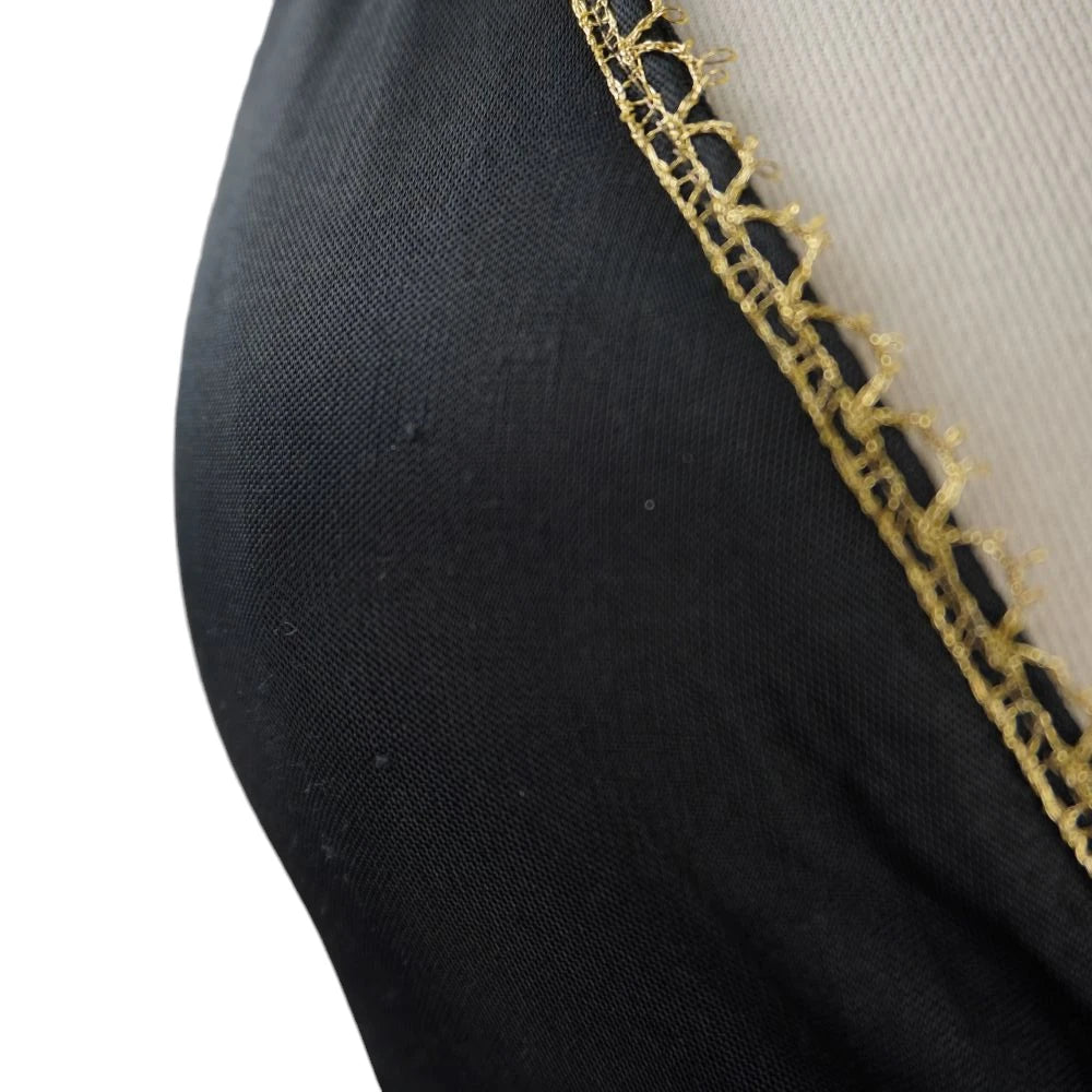 Primo piano dello scollo a V di un vestito nero con finitura in pizzo metallico dorato.