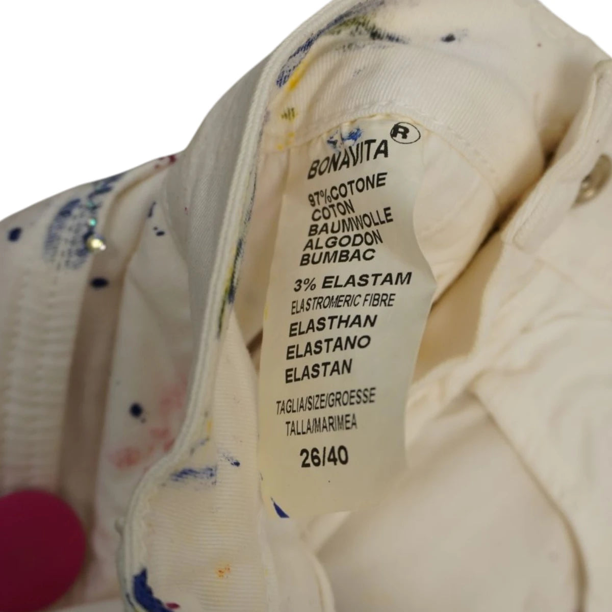 Primo piano dell'etichetta interna in tessuto con le istruzioni di lavaggio, la composizione in cotone ed elastam e l'indicazione della taglia vintage 26.