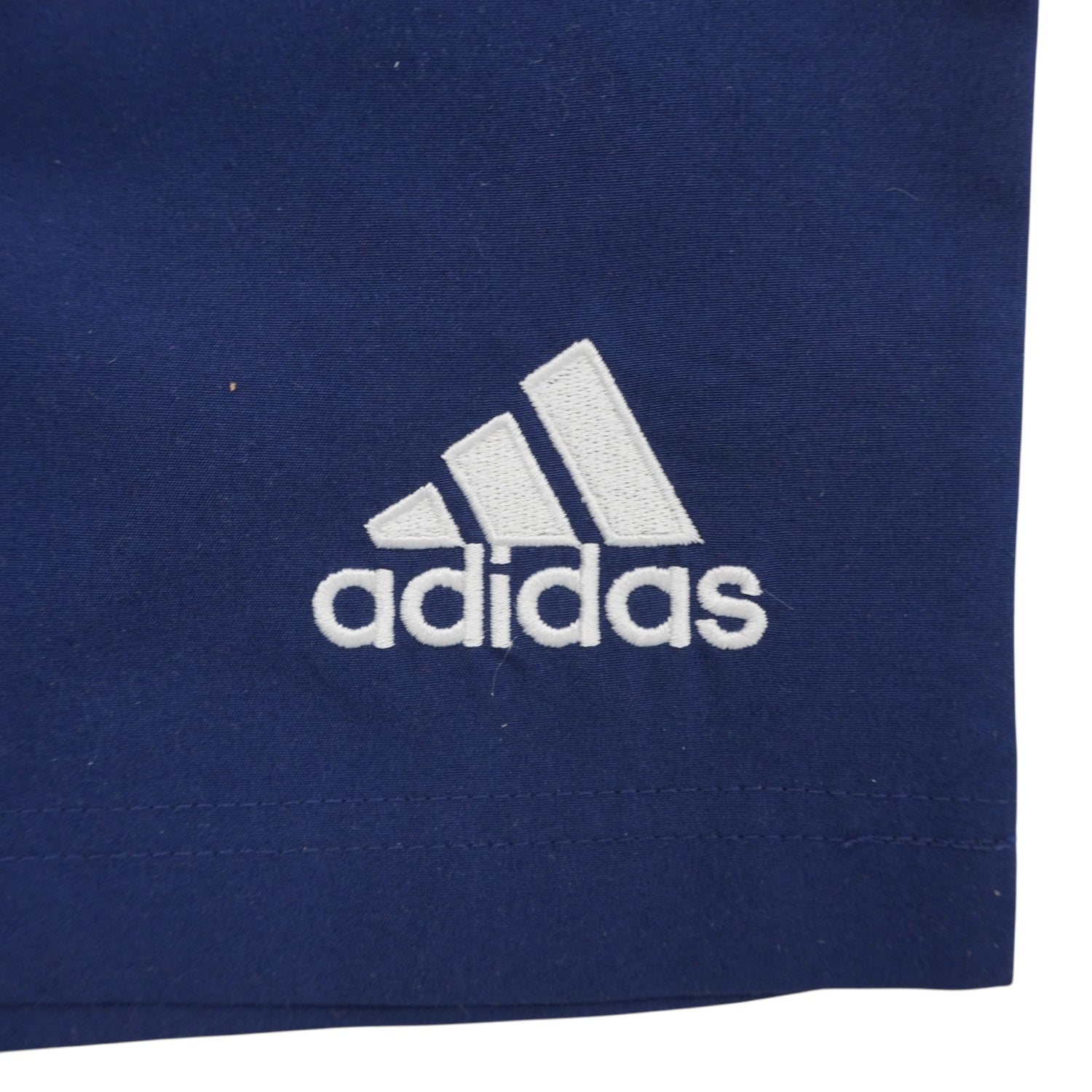 Inquadratura ravvicinata del logo Performance adidas originale ricamato con filo bianco sulla gamba sinistra