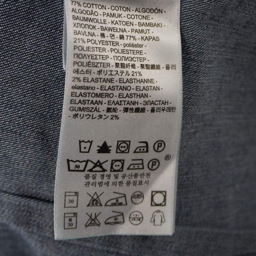 Primo piano dei simboli internazionali per il lavaggio e la cura della camicia di jeans a 30 gradi.