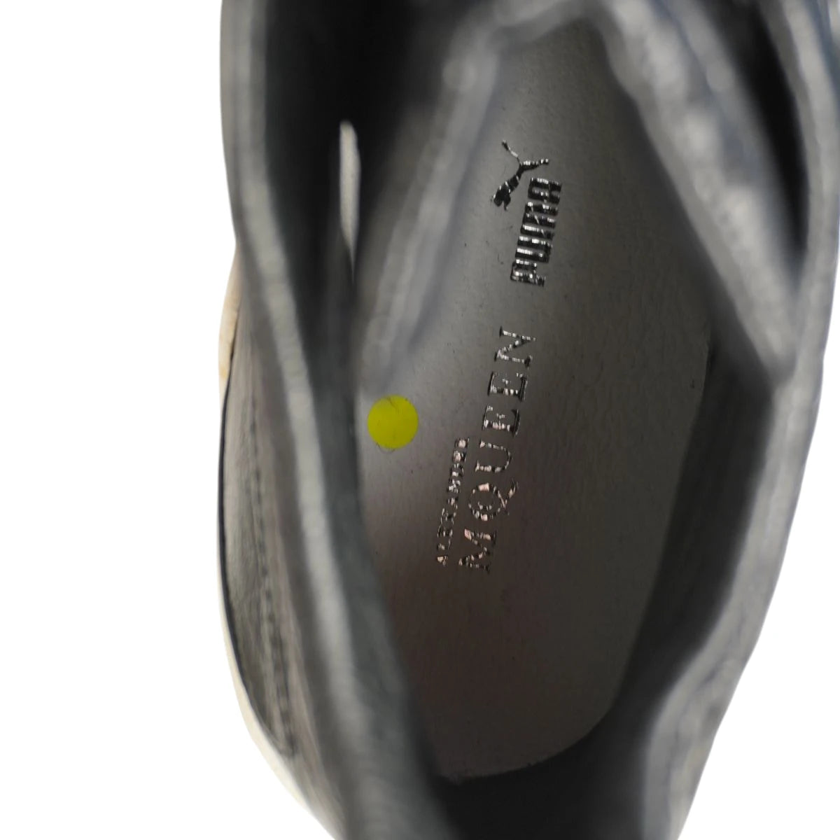 Vista interna della soletta in pelle grigia con loghi laminati argento Puma Alexander McQueen e bollino di controllo giallo