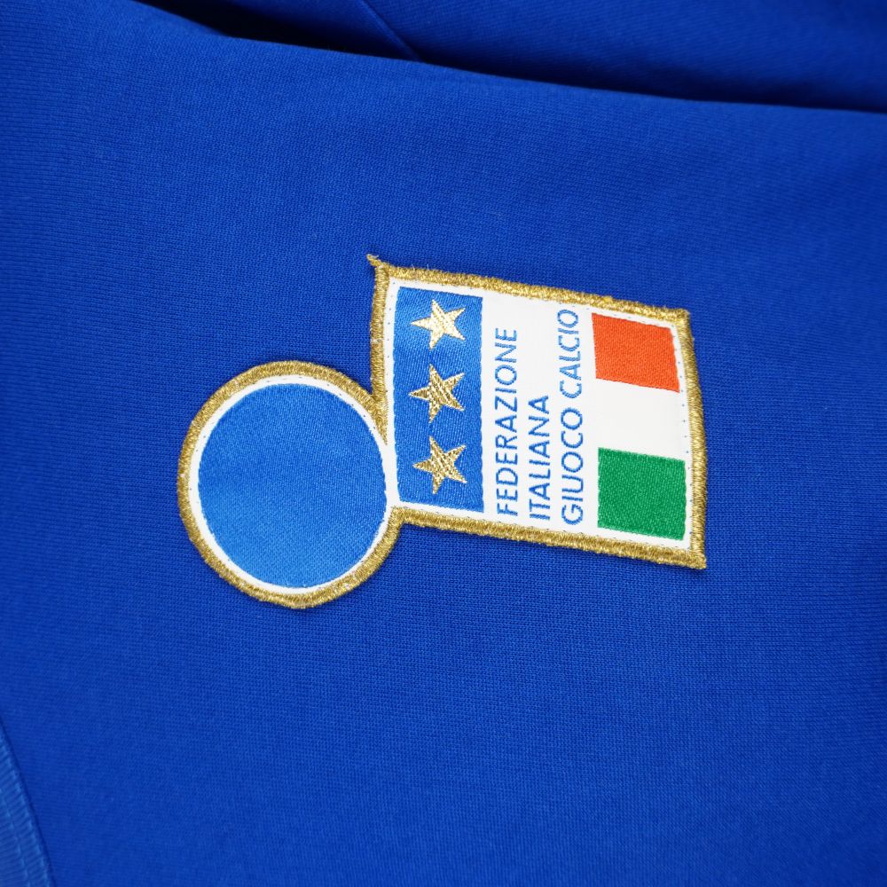 Primo piano dello stemma FIGC ricamato sul petto con tre stelle d'oro e bandiera italiana