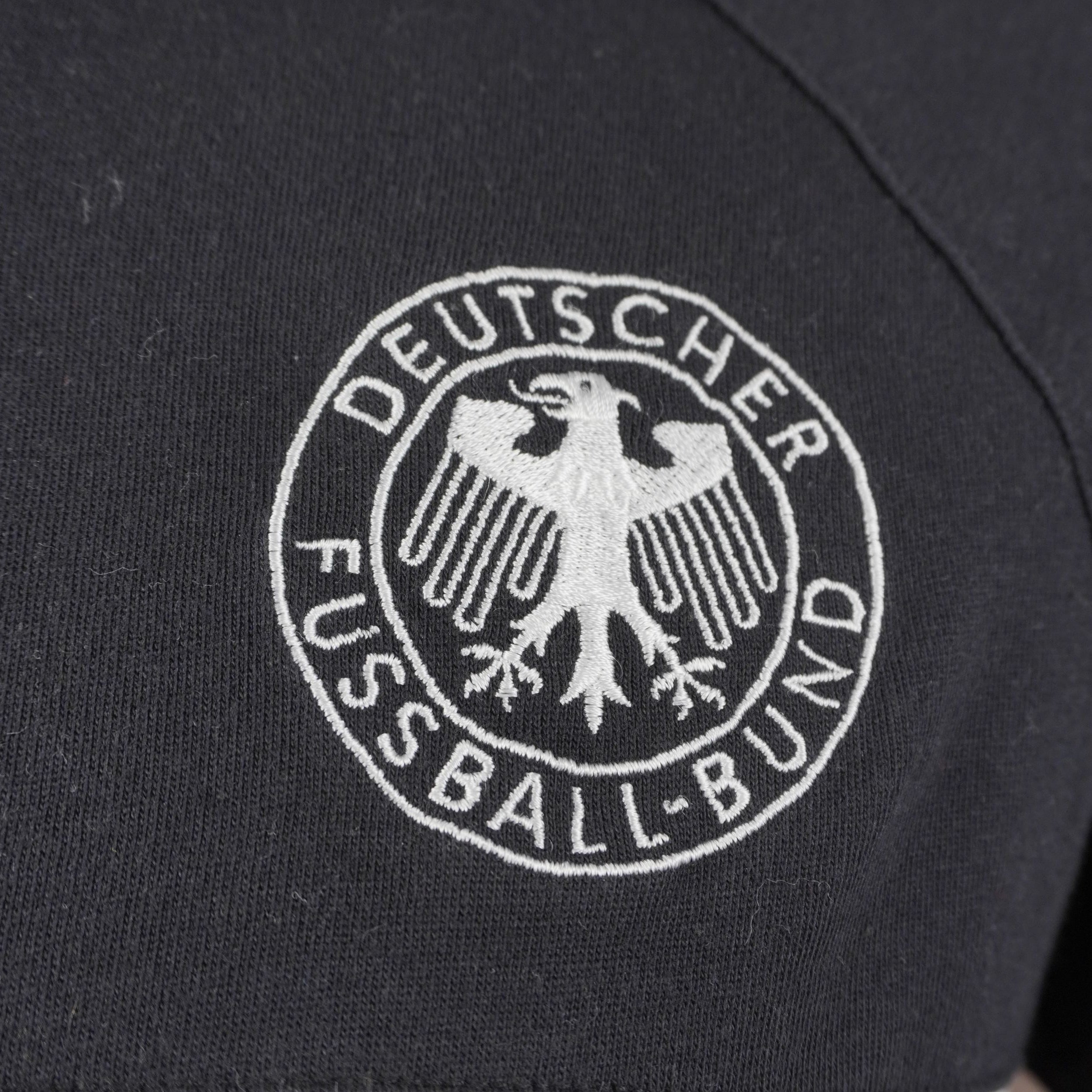 Dettaglio dello stemma ufficiale della federazione calcistica tedesca Deutscher Fussball-Bund ricamato in bianco e nero su tessuto.