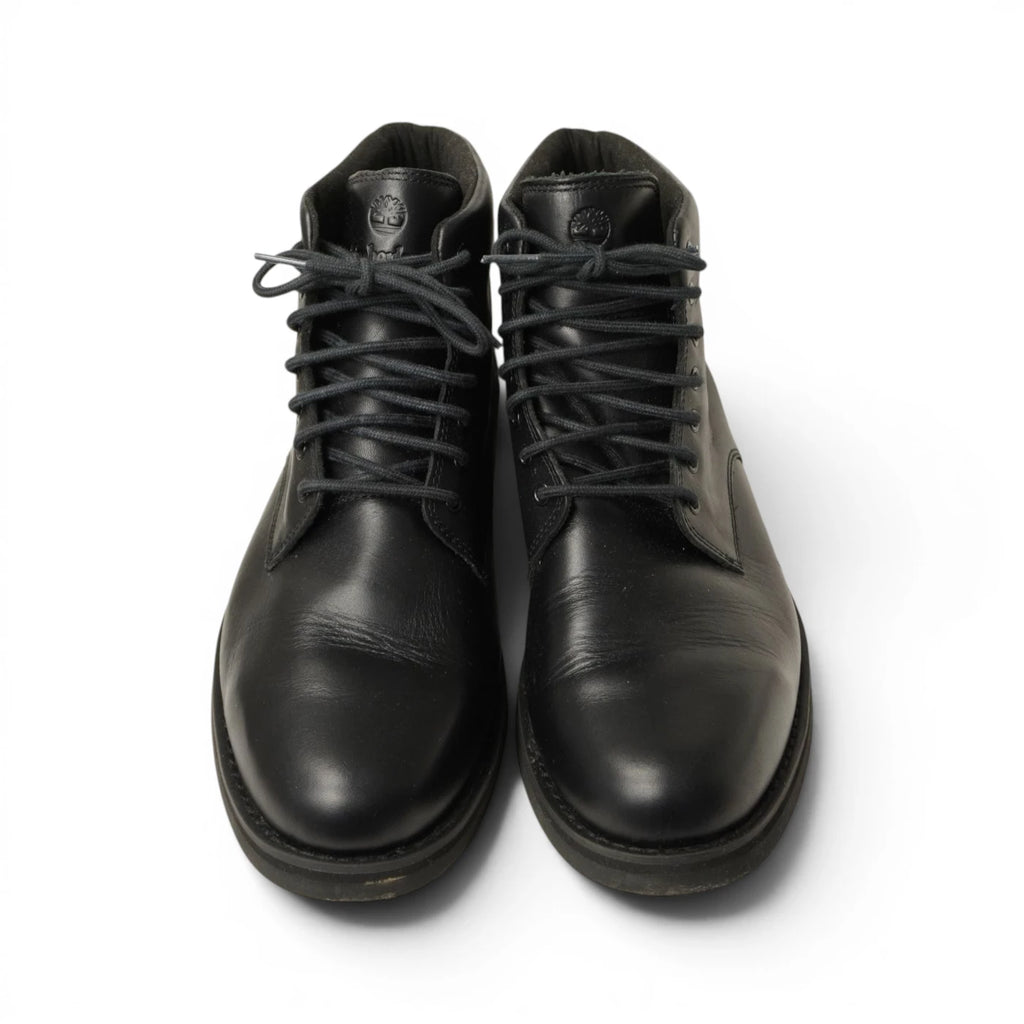 Coppia di stivaletti neri Timberland inquadrati frontalmente con lacci neri e linguetta logata ben visibile.