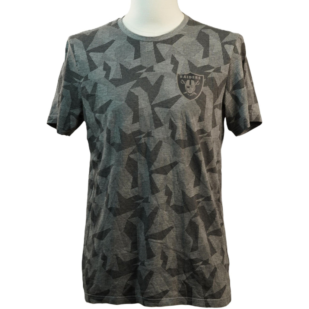 Vista frontale di una t-shirt grigia a maniche lunghe corte con stampa geometrica mimetica all-over, logo dei Las Vegas Raiders sul petto e manichino bianco.
