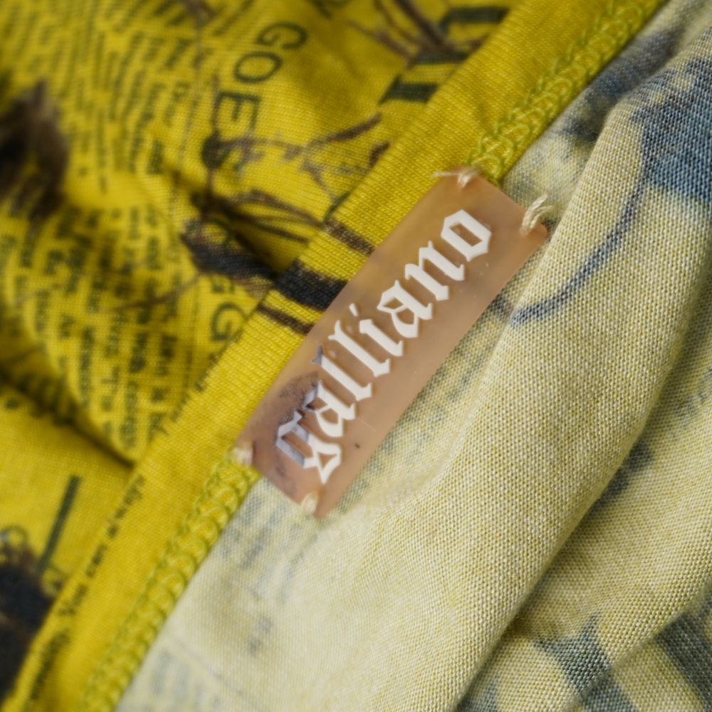  Dettaglio ravvicinato dell'etichetta marrone in tessuto con il logo Galliano cucita all'interno dello scollo.