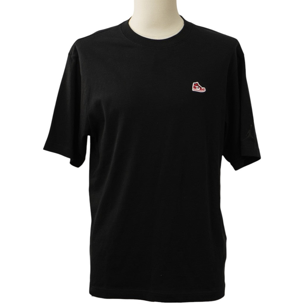 Vista frontale della T-shirt Jordan nera su manichino con patch ricamata sul petto.