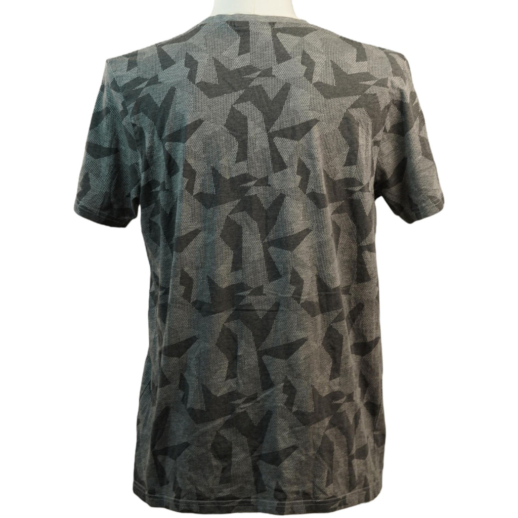 Vista posteriore della t-shirt grigia con motivo camouflage geometrico continuo stampato su tutta la schiena.
