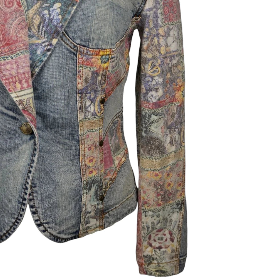Dettaglio del fianco sciancrato del blazer in denim con file di borchie metalliche brunite decorative.