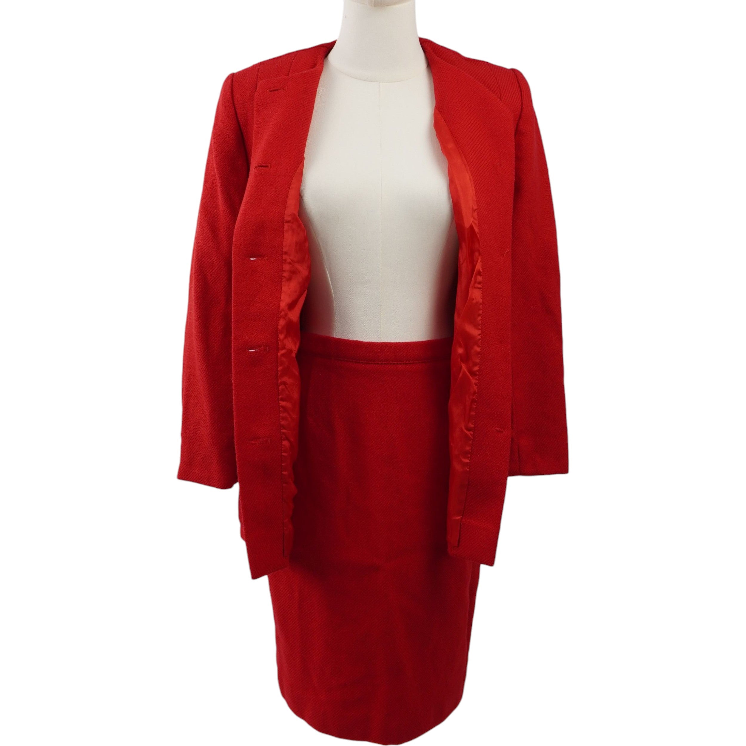 Tailleur rosso con giacca aperta indossata sopra un sottogiacca, abbinata alla gonna coordinata.