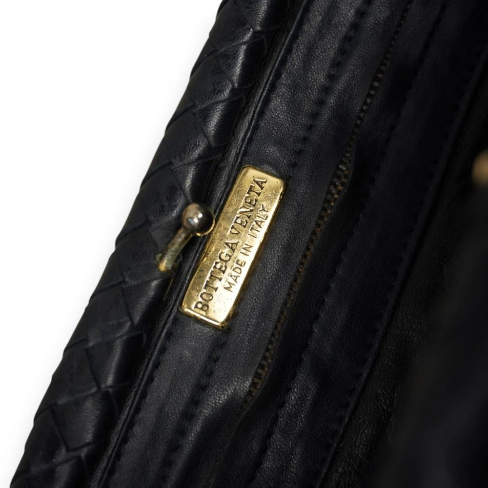 Dettaglio della targhetta rettangolare in metallo dorato Bottega Veneta Made in Italy all'interno della borsa.