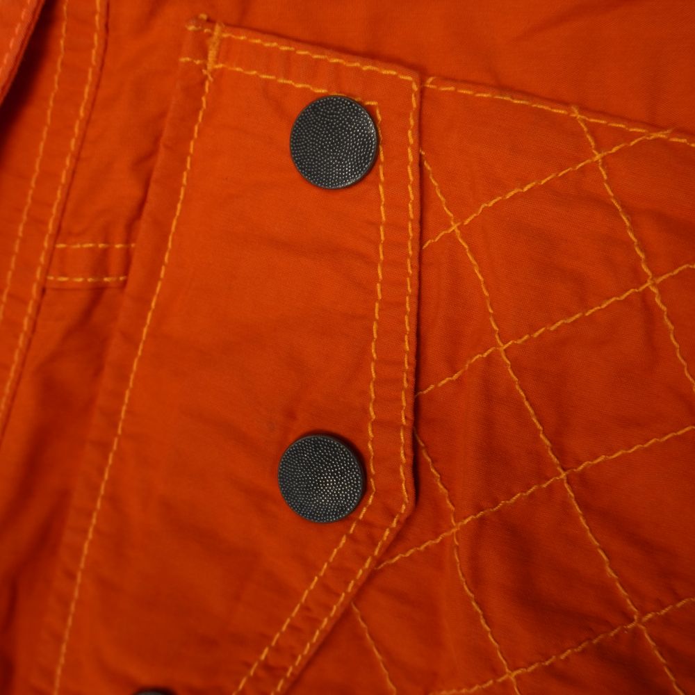 Dettaglio della tasca posteriore dei pantaloni Diesel con patta geometrica, bottoni automatici neri e texture trapuntata a rombi.